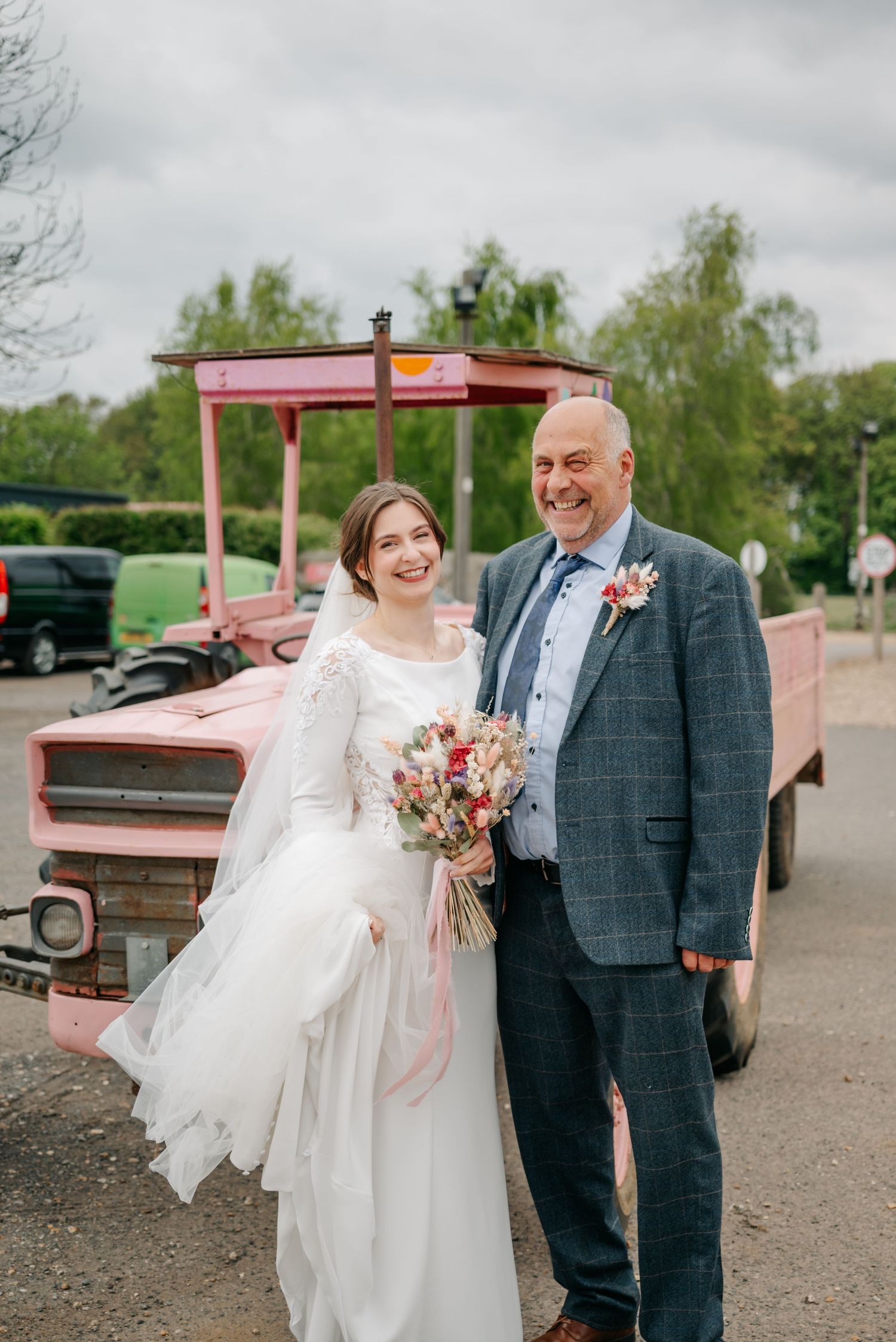 Wedding party poses with vintage pink pickup truck on overcast day.