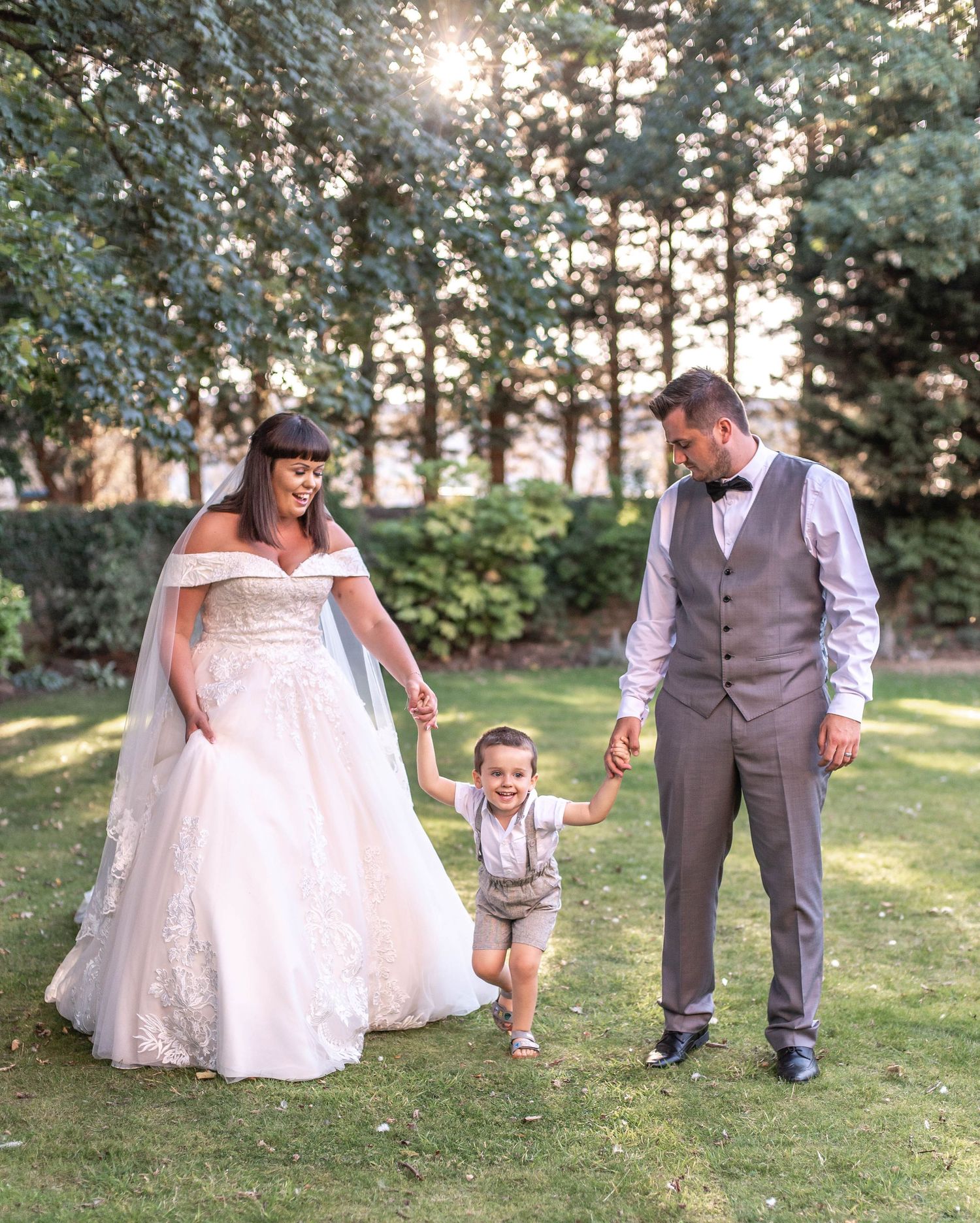 A family shares a joyful moment together on their wedding day in a sunlit garden.