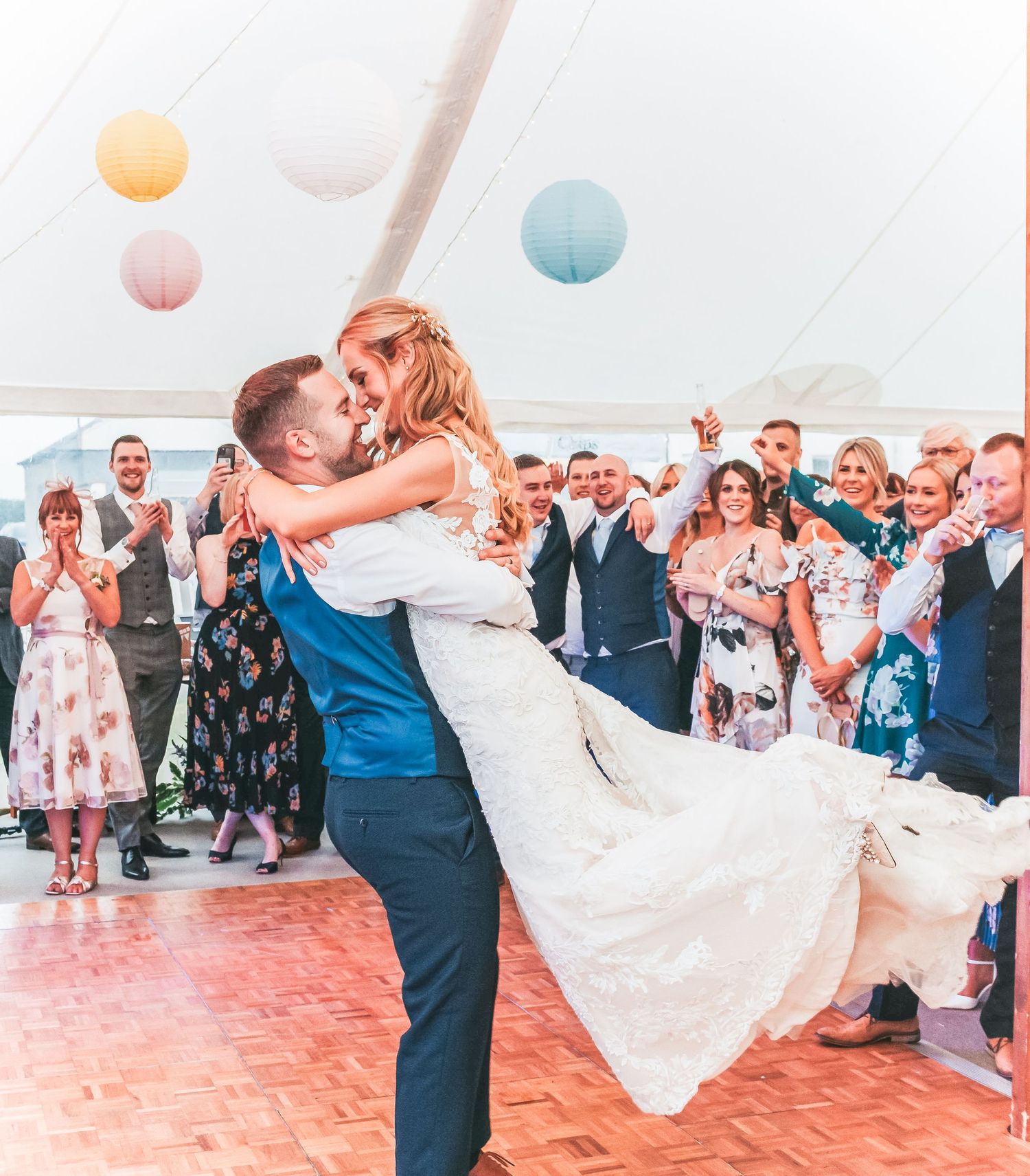 First dance moment during wedding reception with guests cheering in background.
