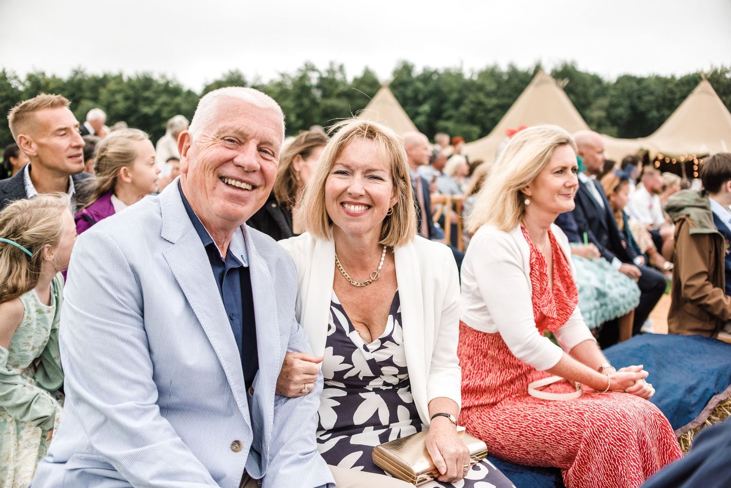 Guests smiling and laughing while seated at an outdoor event.