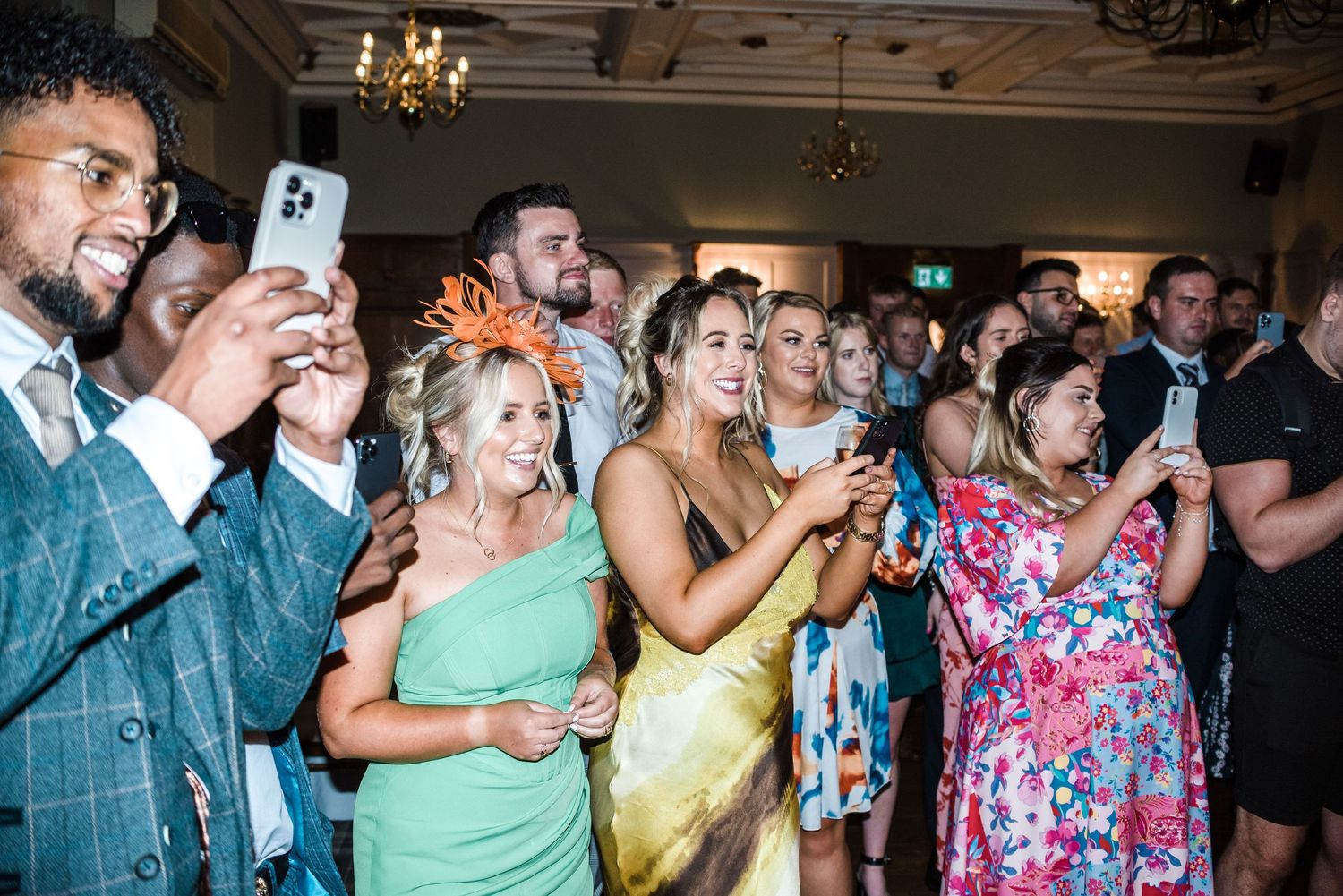 Wedding guests capturing moments on phones during reception celebration.