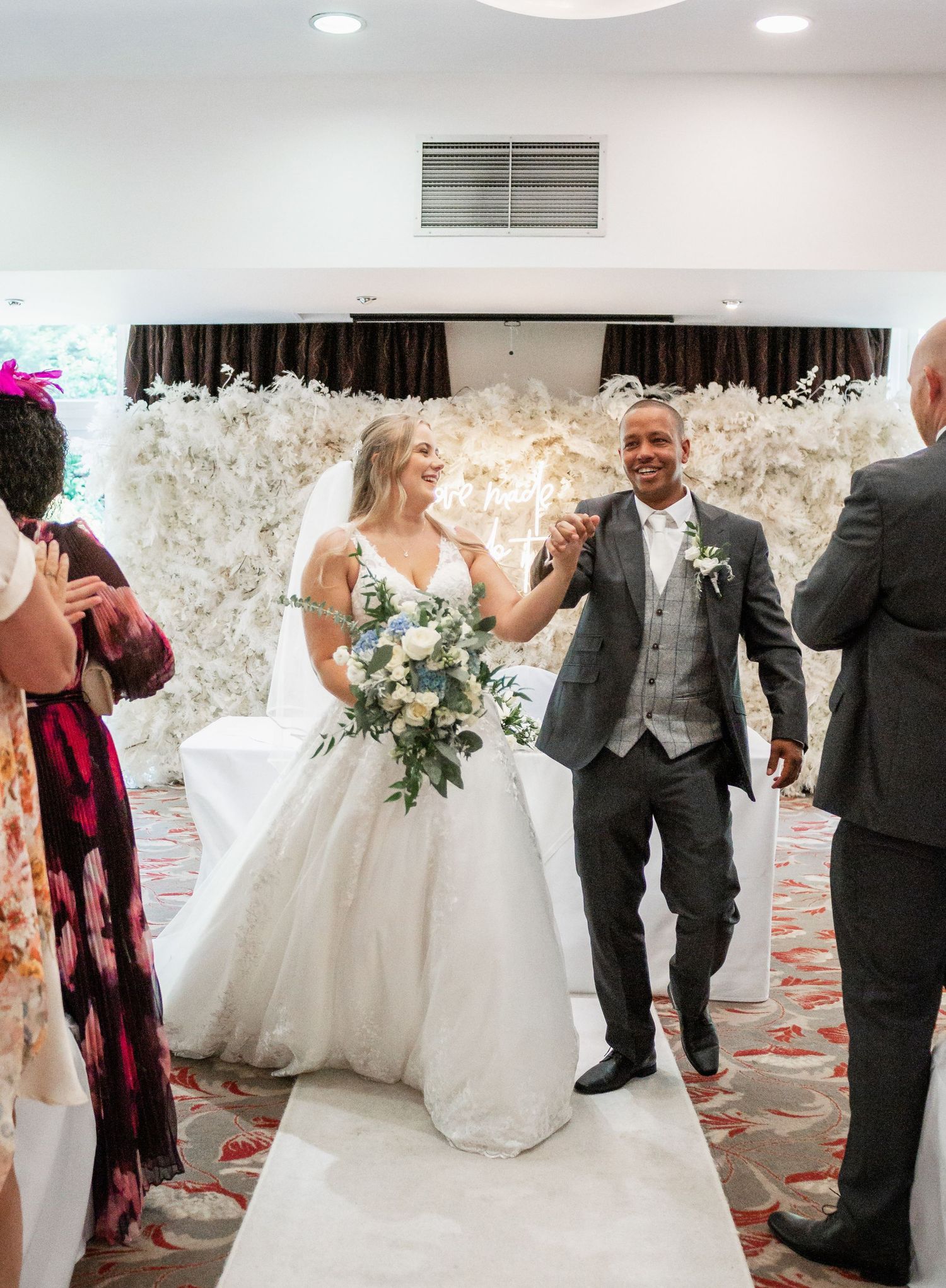 Newlyweds celebrate while walking down aisle in elegant ceremony space.