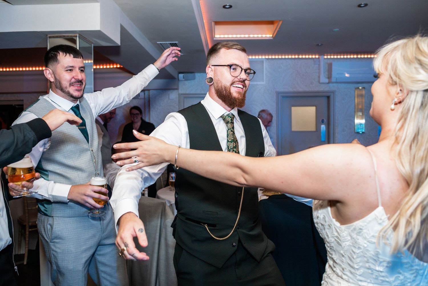 Energetic dancing scene at wedding reception with decorative lighting and festive atmosphere.