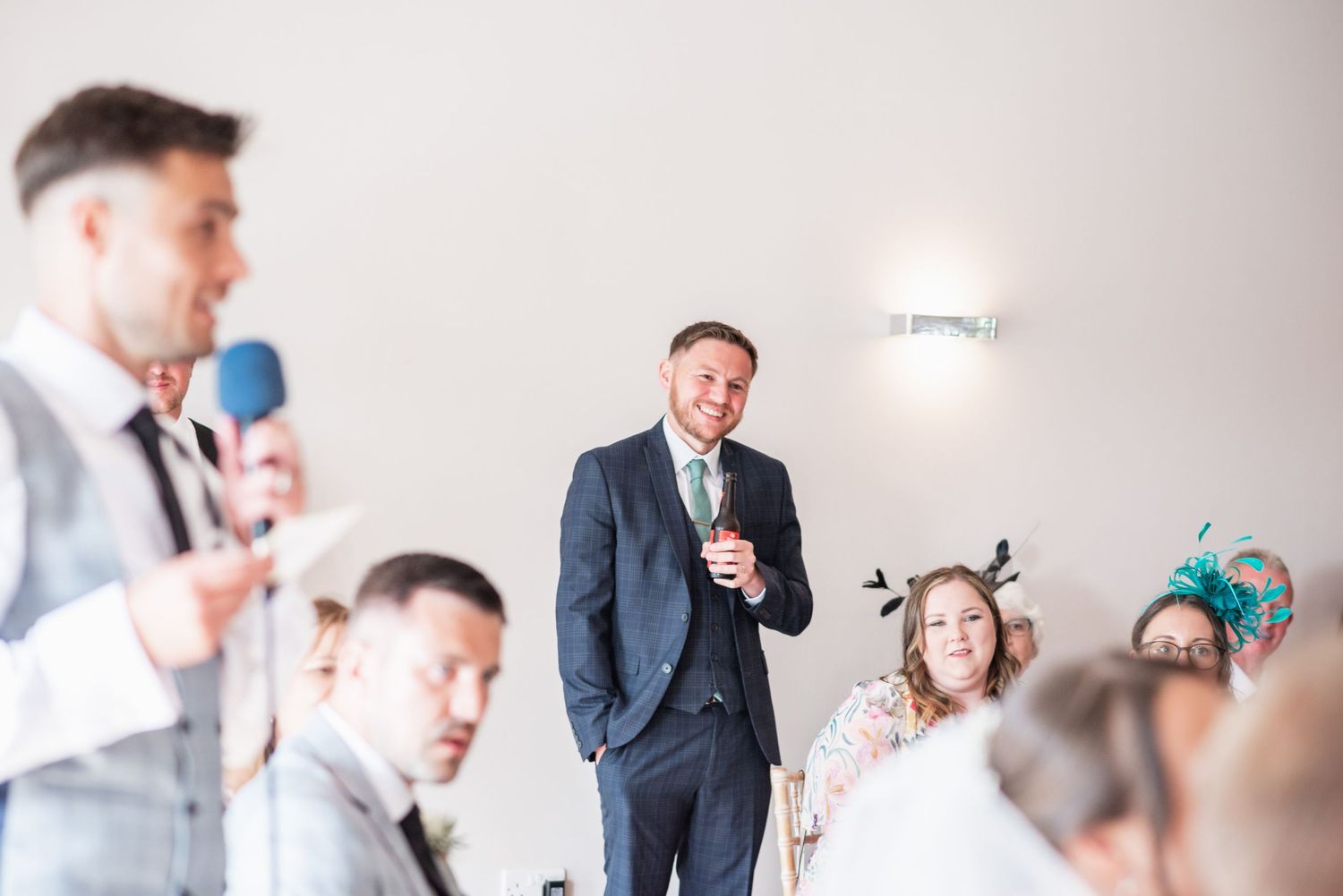 Wedding reception guests listening to speeches in formal attire.