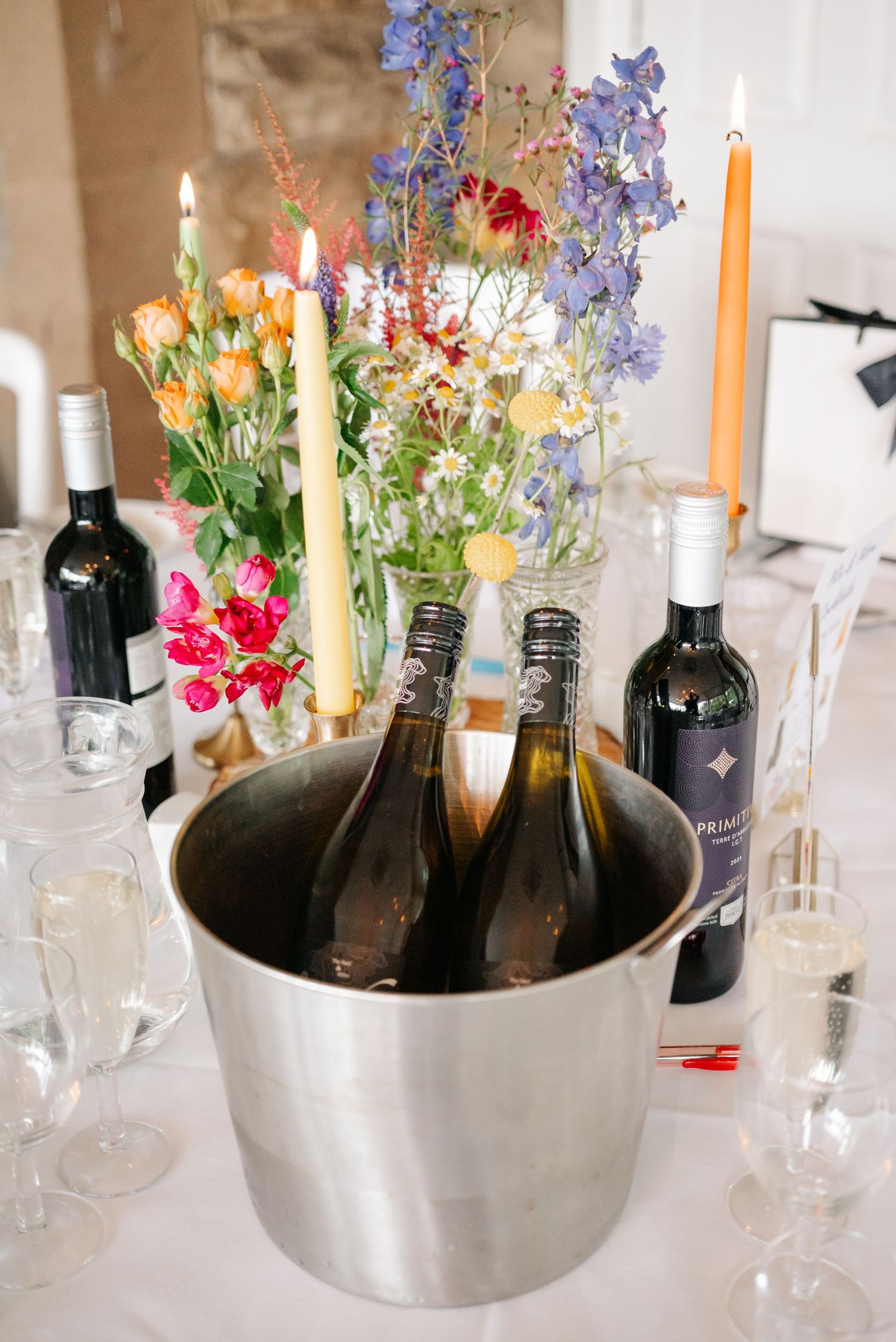 Wine bottles chill in an ice bucket alongside delicate floral centerpieces and lit candles.