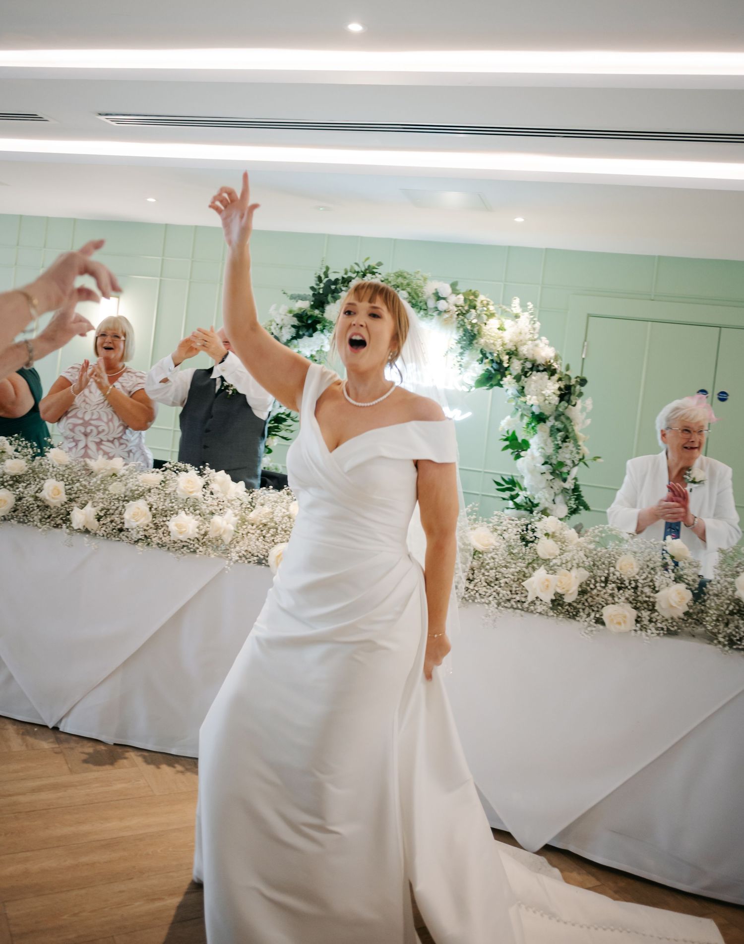 A bride in a white wedding gown dances joyfully at her reception celebration.