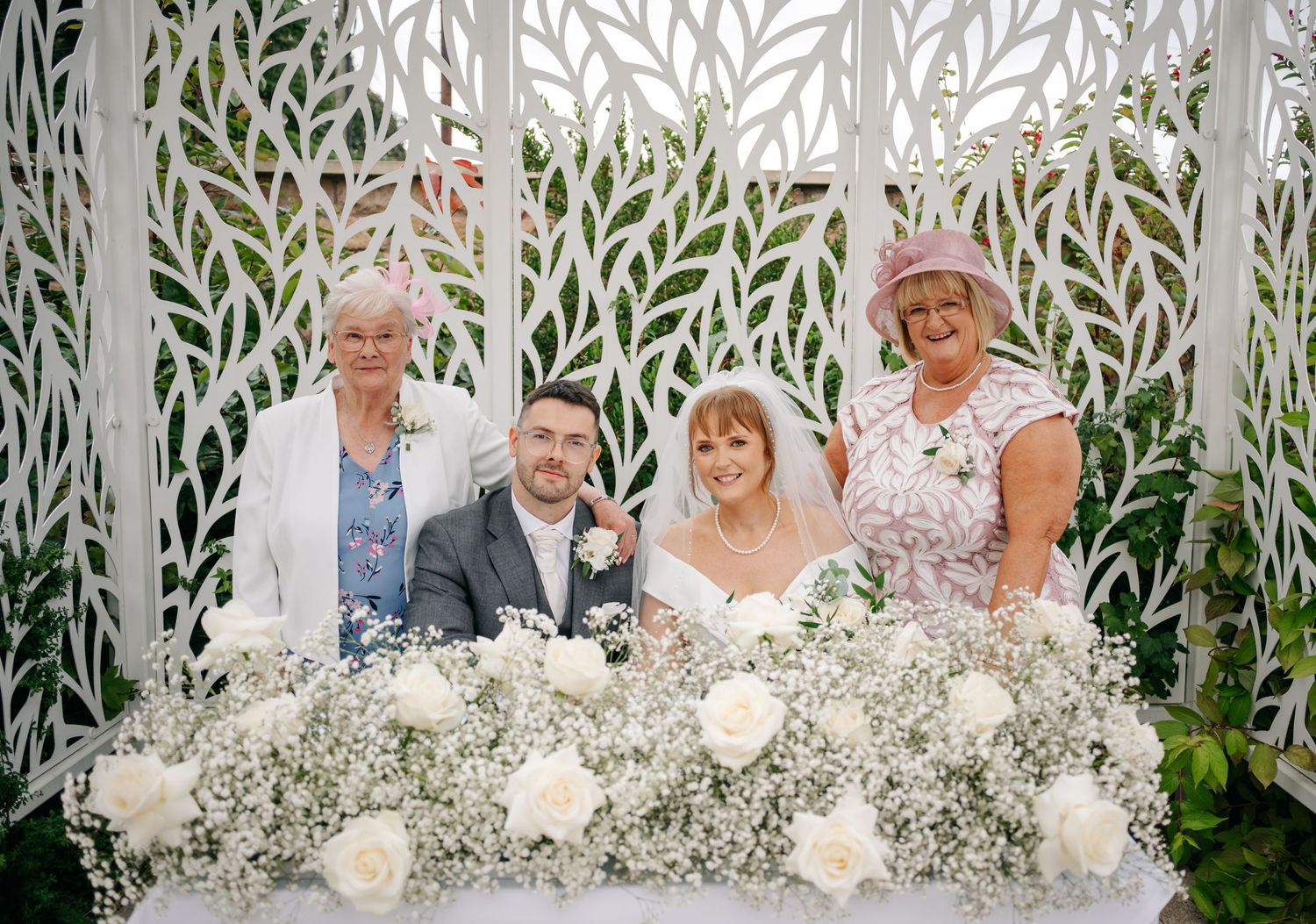 Wedding ceremony signing moment under a white pergola decorated with flowers and greenery.