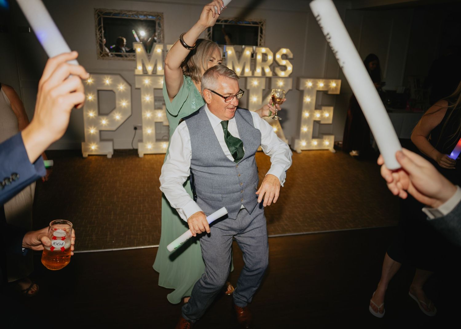 Wedding reception dance floor with illuminated Mr & Mrs sign in the background.