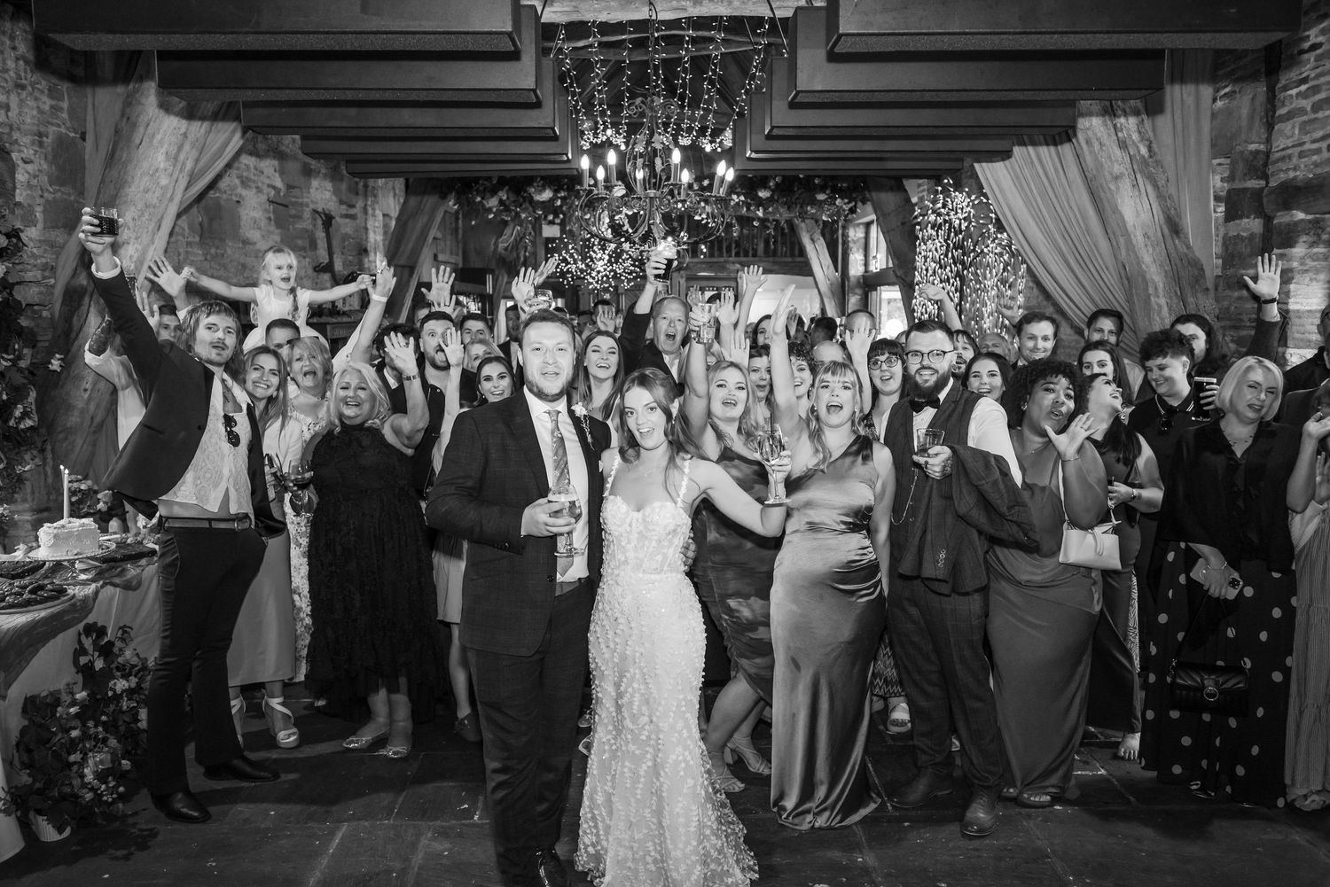 Wedding reception dance party with guests celebrating under mood lighting and confetti.