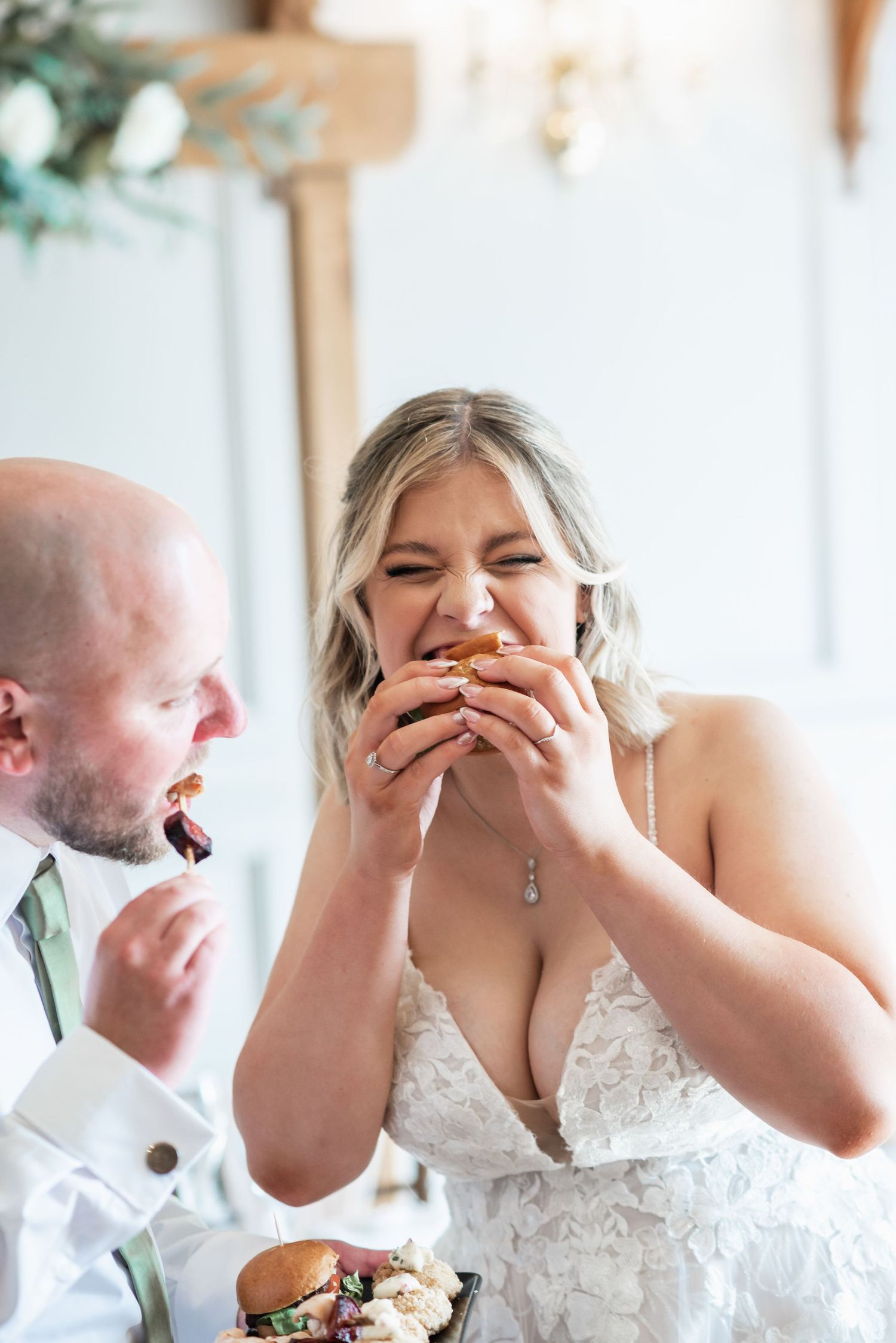 Newlyweds share a joyful moment while eating at their wedding reception table.