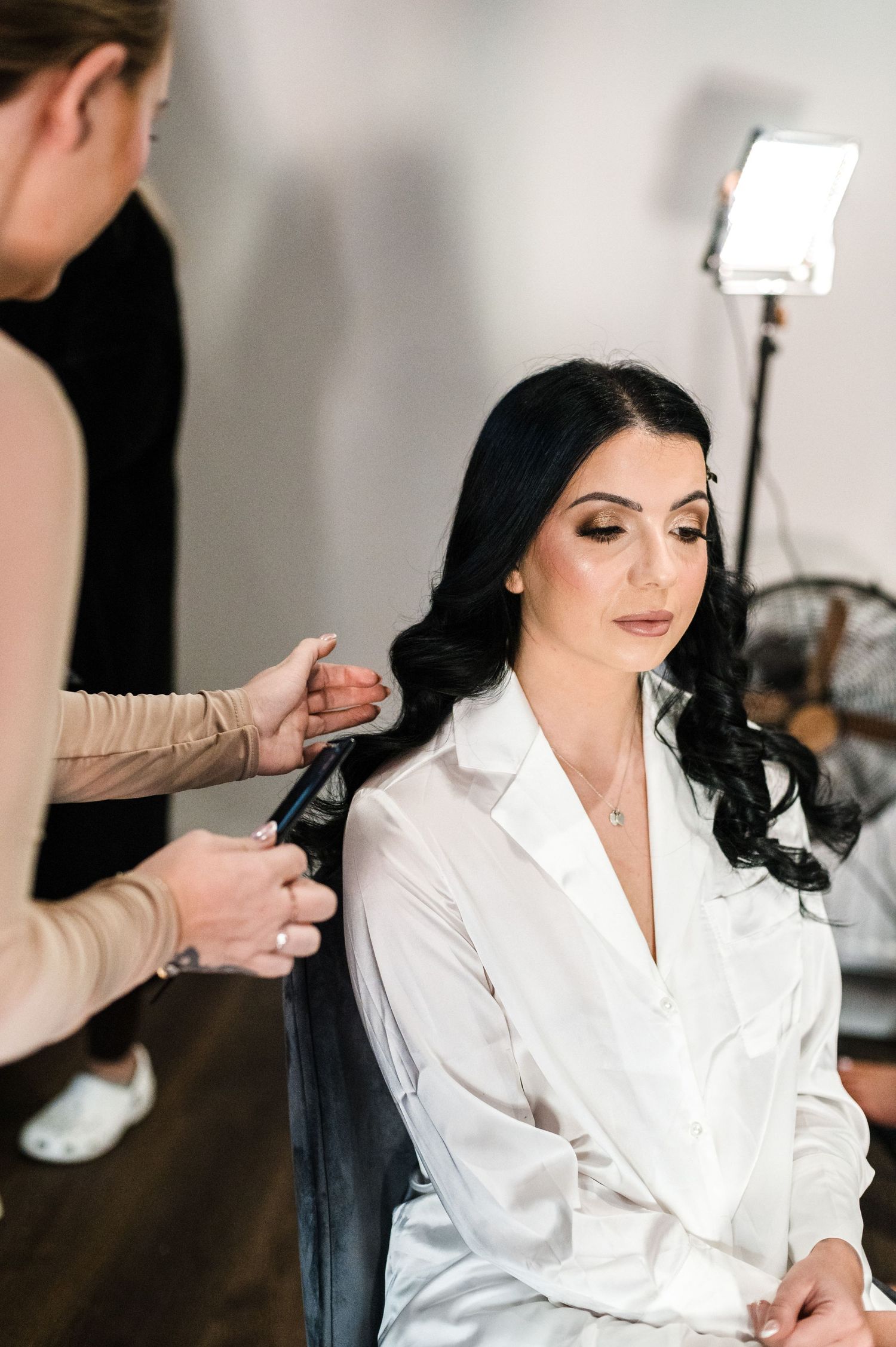 Hair stylist working on bride's hairstyle during wedding preparations.