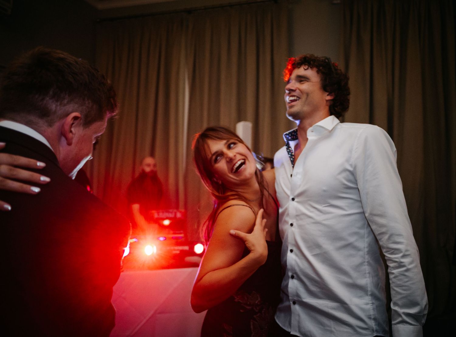 Dance floor illuminated with red lighting at an evening wedding reception.