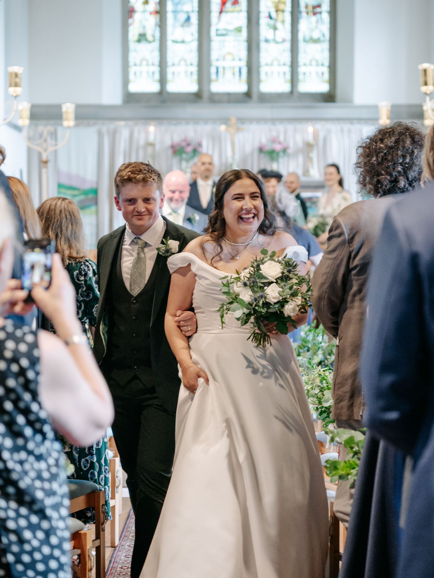 Joyful celebration inside a church with stained glass windows and floral decorations.