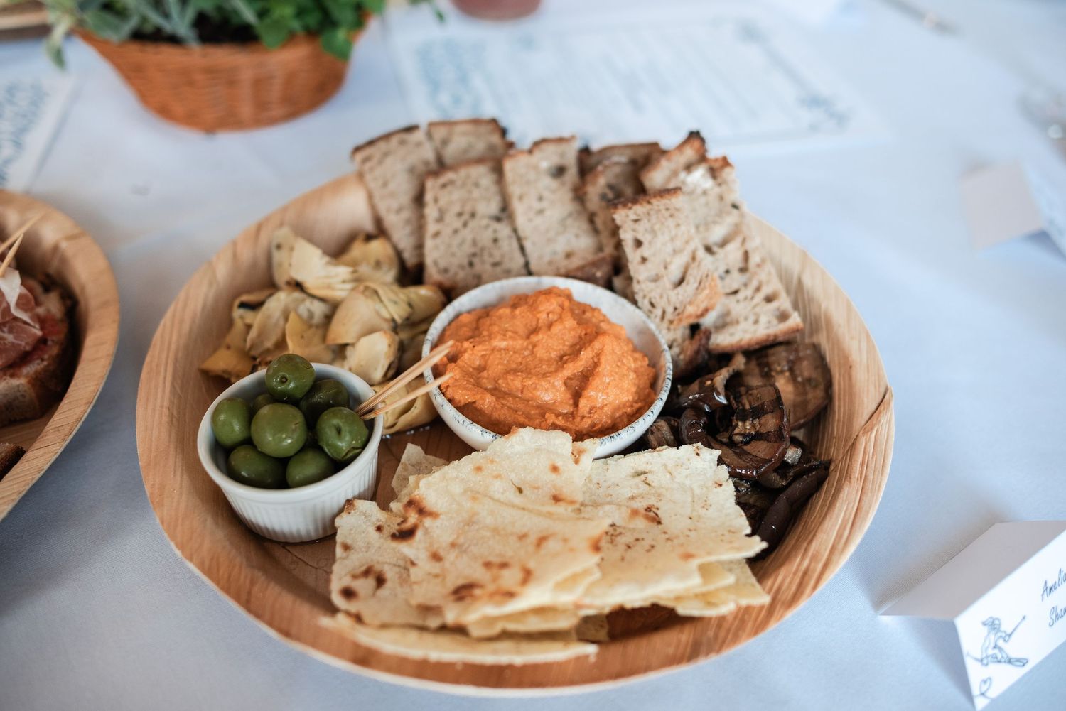 A Mediterranean-style spread of flatbreads, dips, olives and various appetizers arranged on clay plates.