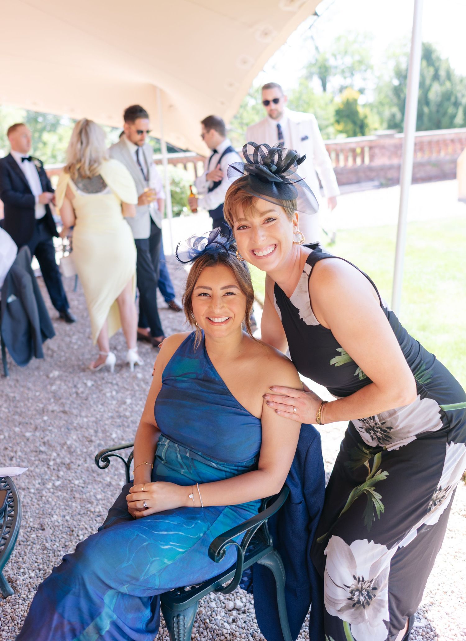 Wedding guests in formal attire sharing joyful moments outdoors.