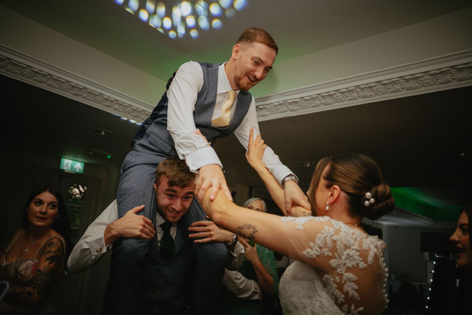 Wedding reception dance floor filled with guests celebrating under dimmed lighting.