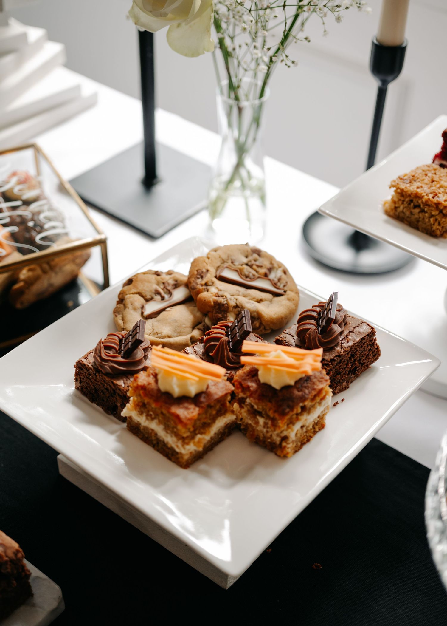 Elegant dessert display featuring brownies and pastries on white plates.