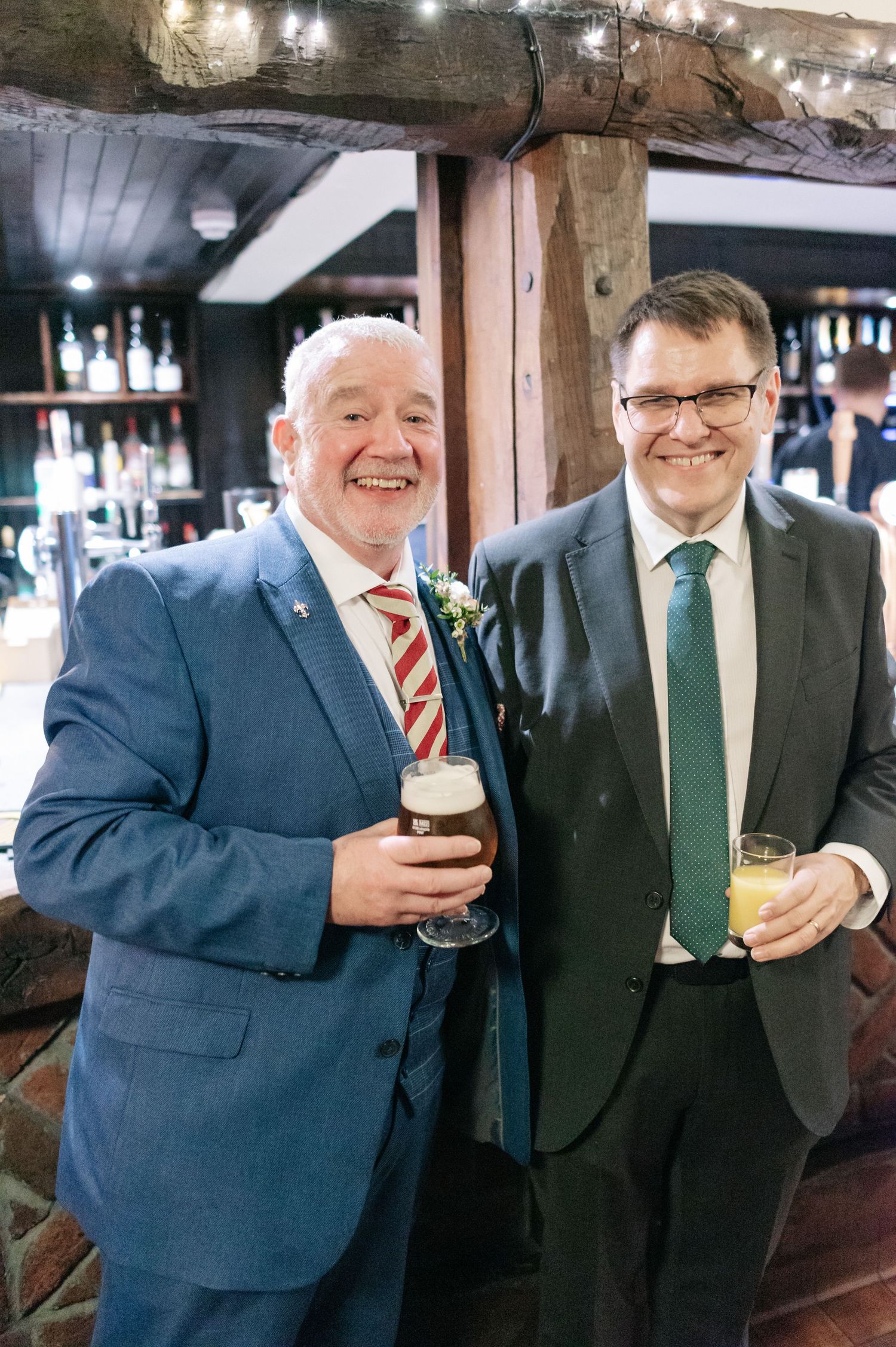 Wedding guests enjoy pints of beer at a rustic pub bar.