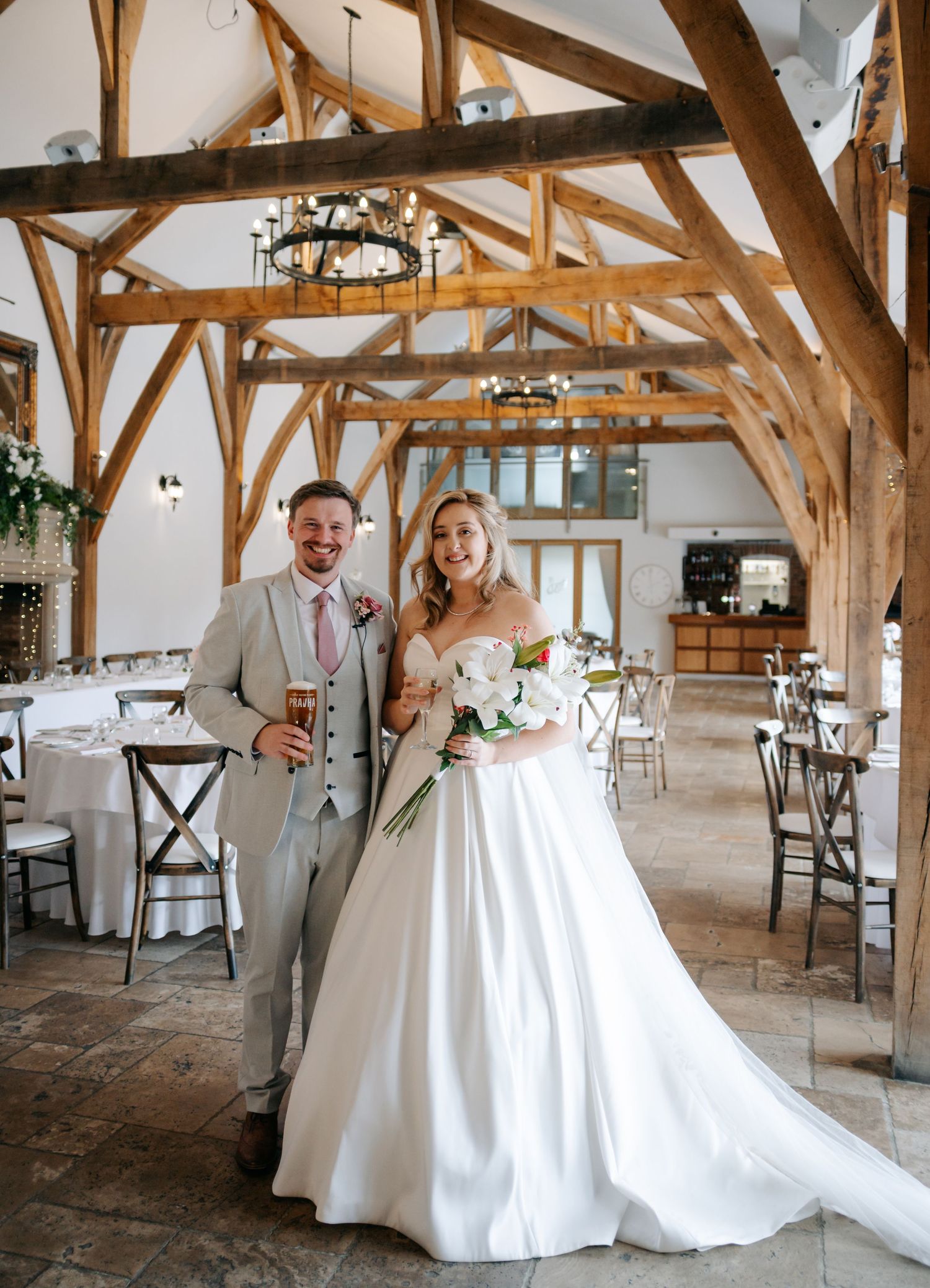 A couple celebrates their wedding day in a rustic barn venue with exposed wooden beams and elegant decor.