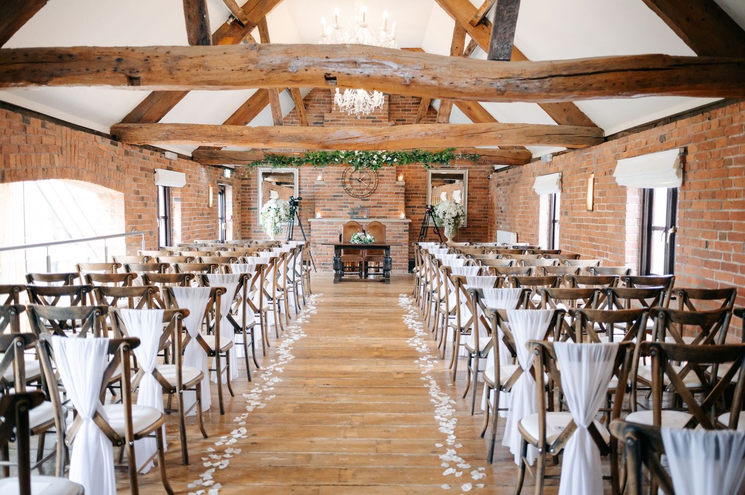 A rustic barn wedding reception venue with exposed wooden beams and rows of elegant table settings.
