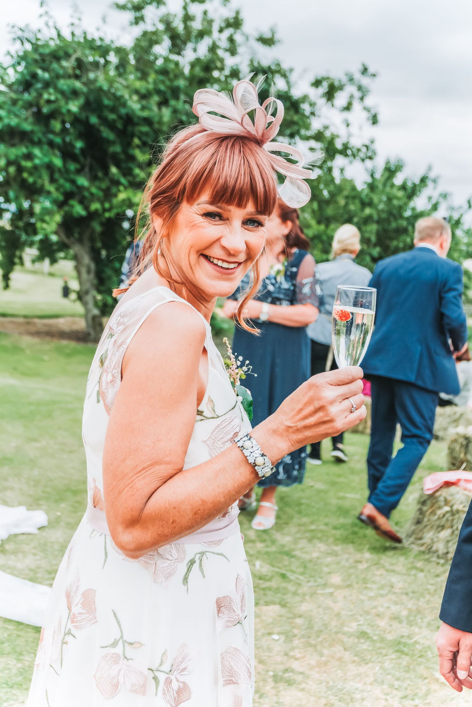 Wedding guest in floral dress enjoying champagne at outdoor garden reception.