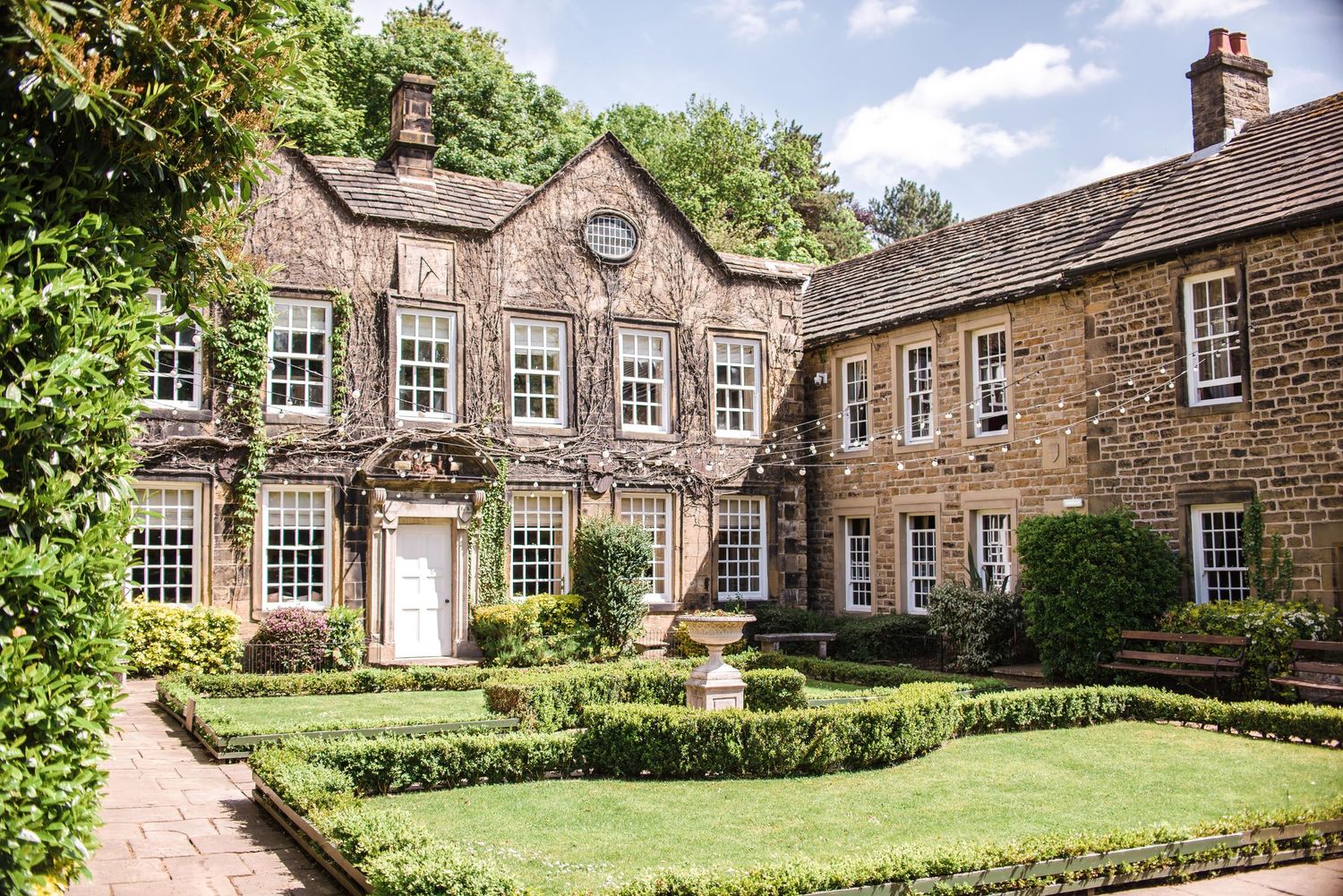 Historic stone mansion with landscaped garden featuring symmetrical windows and grand entrance.