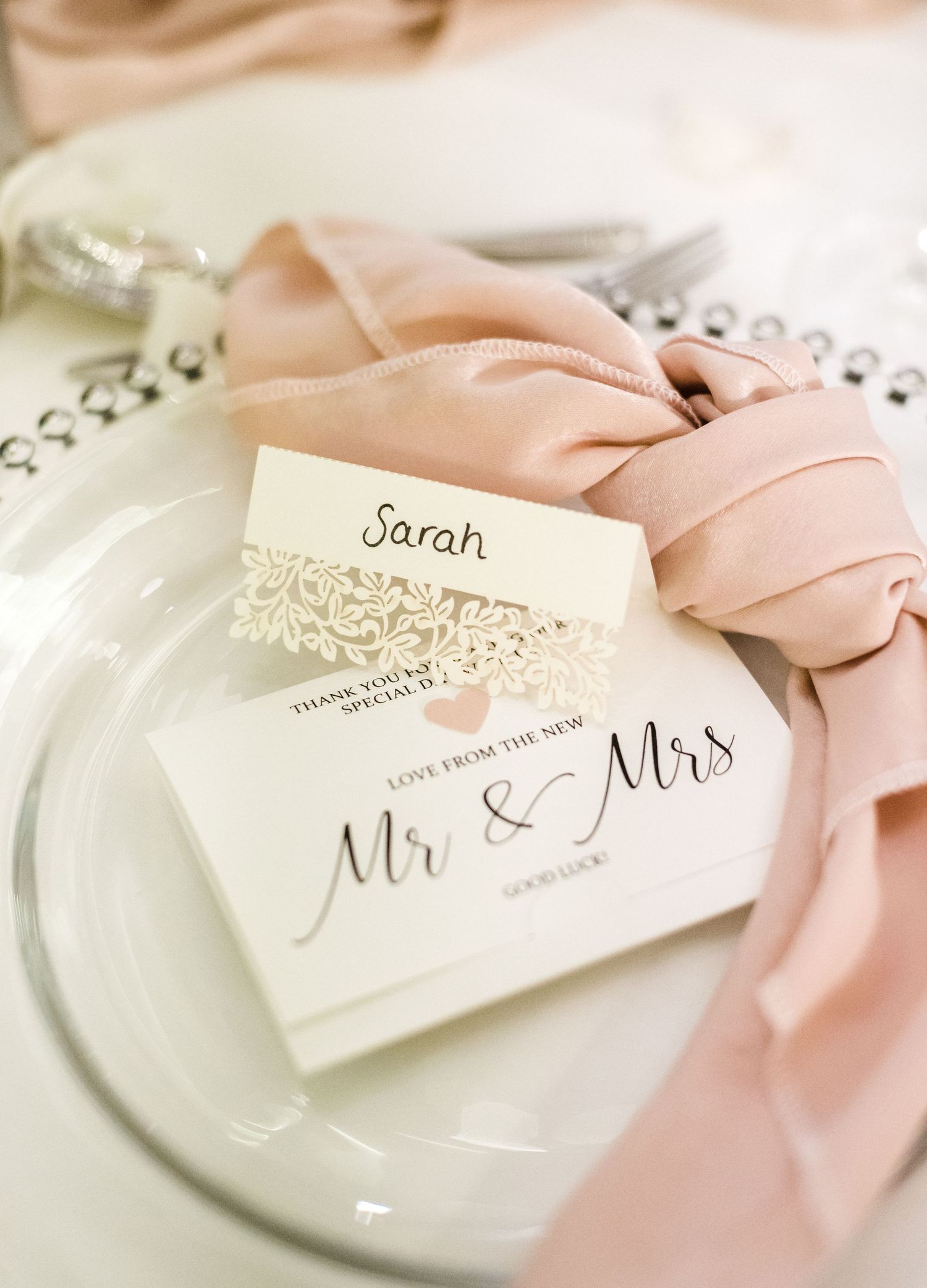 Wedding place setting with blush fabric and elegant Mr & Mrs invitation card.