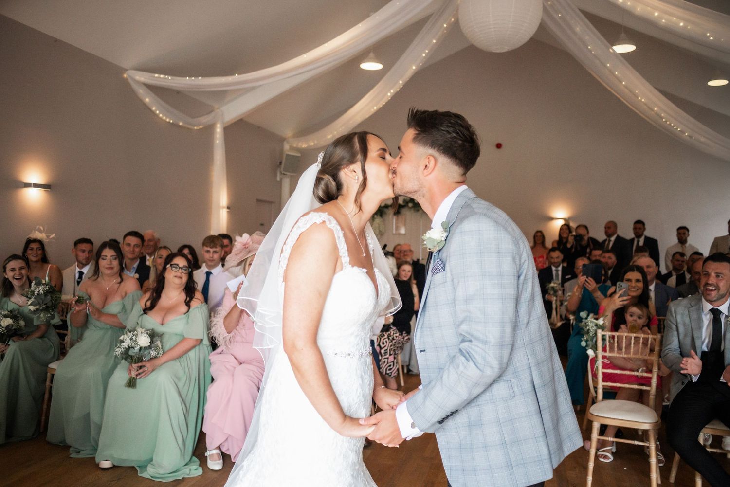 Newlyweds share their first dance under white fabric draping in an elegant reception venue.