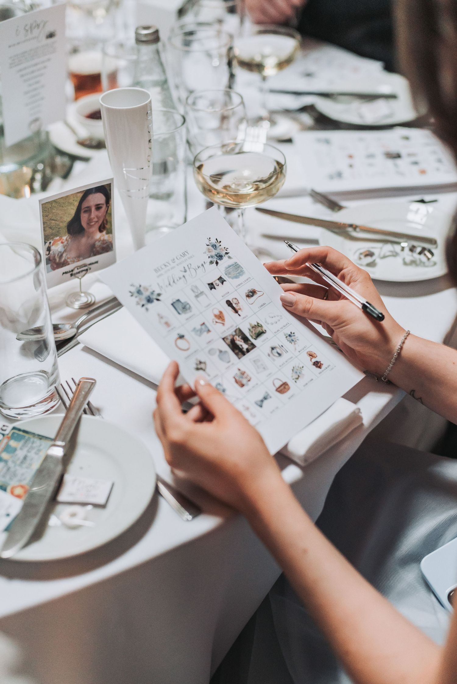 Wedding reception table setting with menu cards and wine glasses.