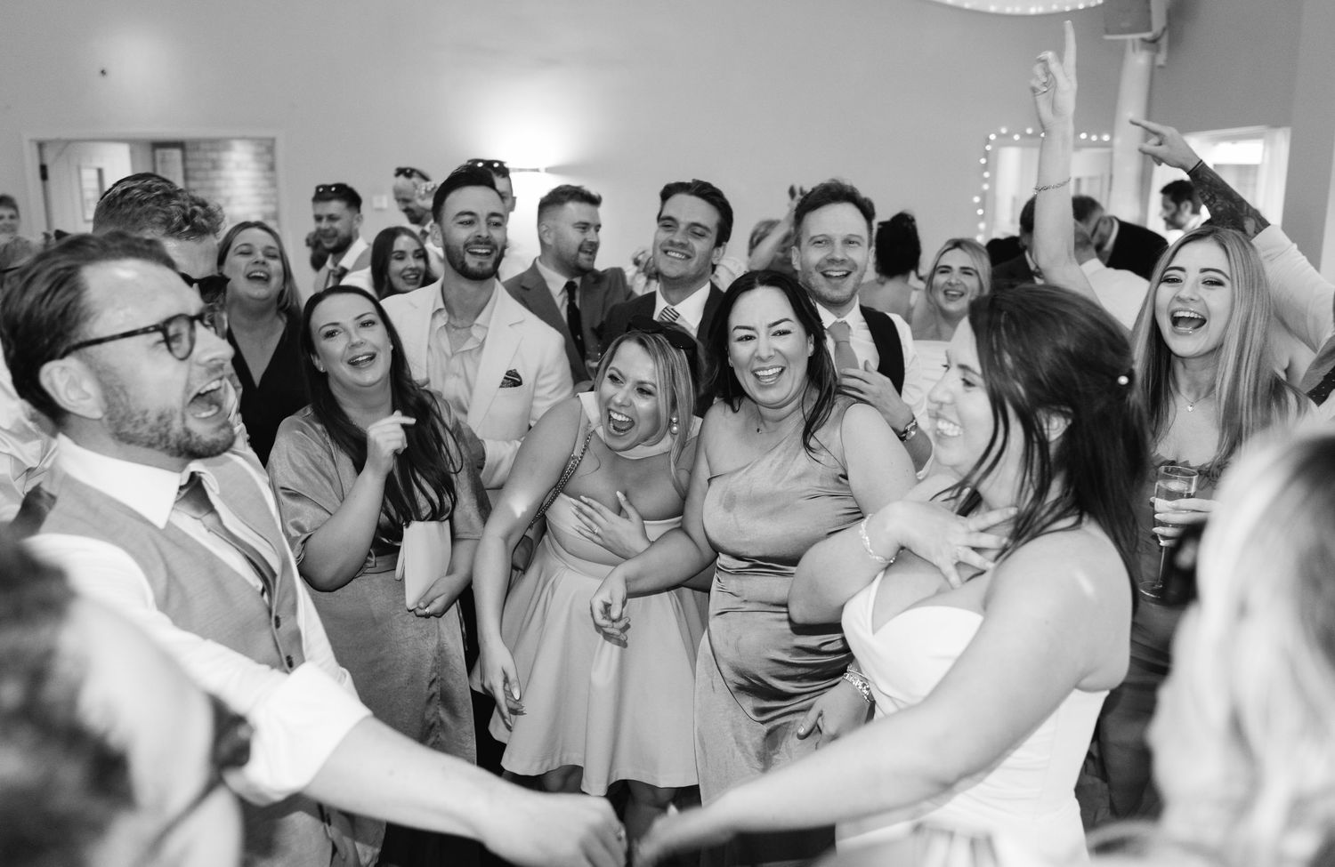 Joyful wedding guests dancing and celebrating together on the dance floor at a lively wedding reception.