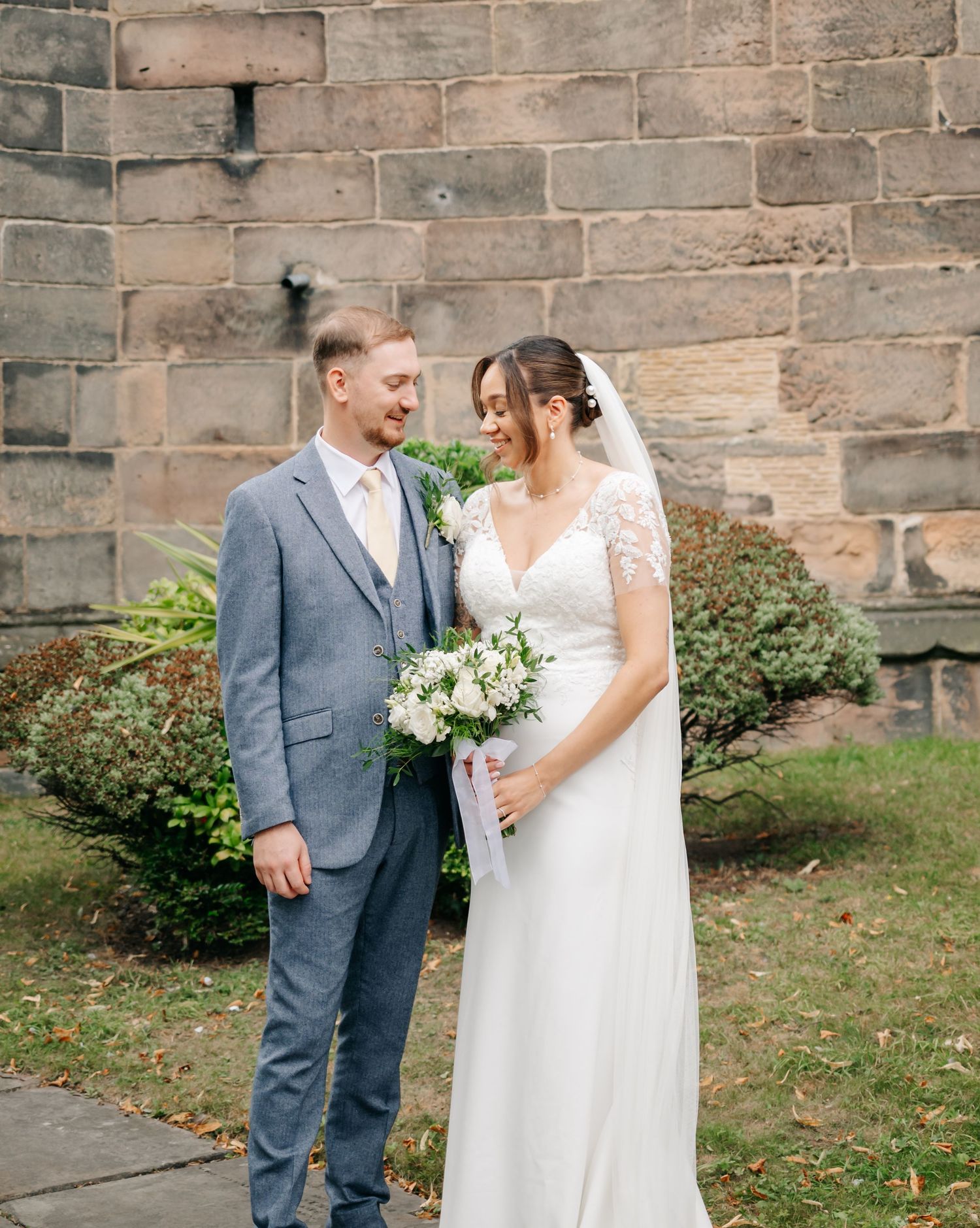 Couple shares intimate moment together outside stone church on their wedding day.