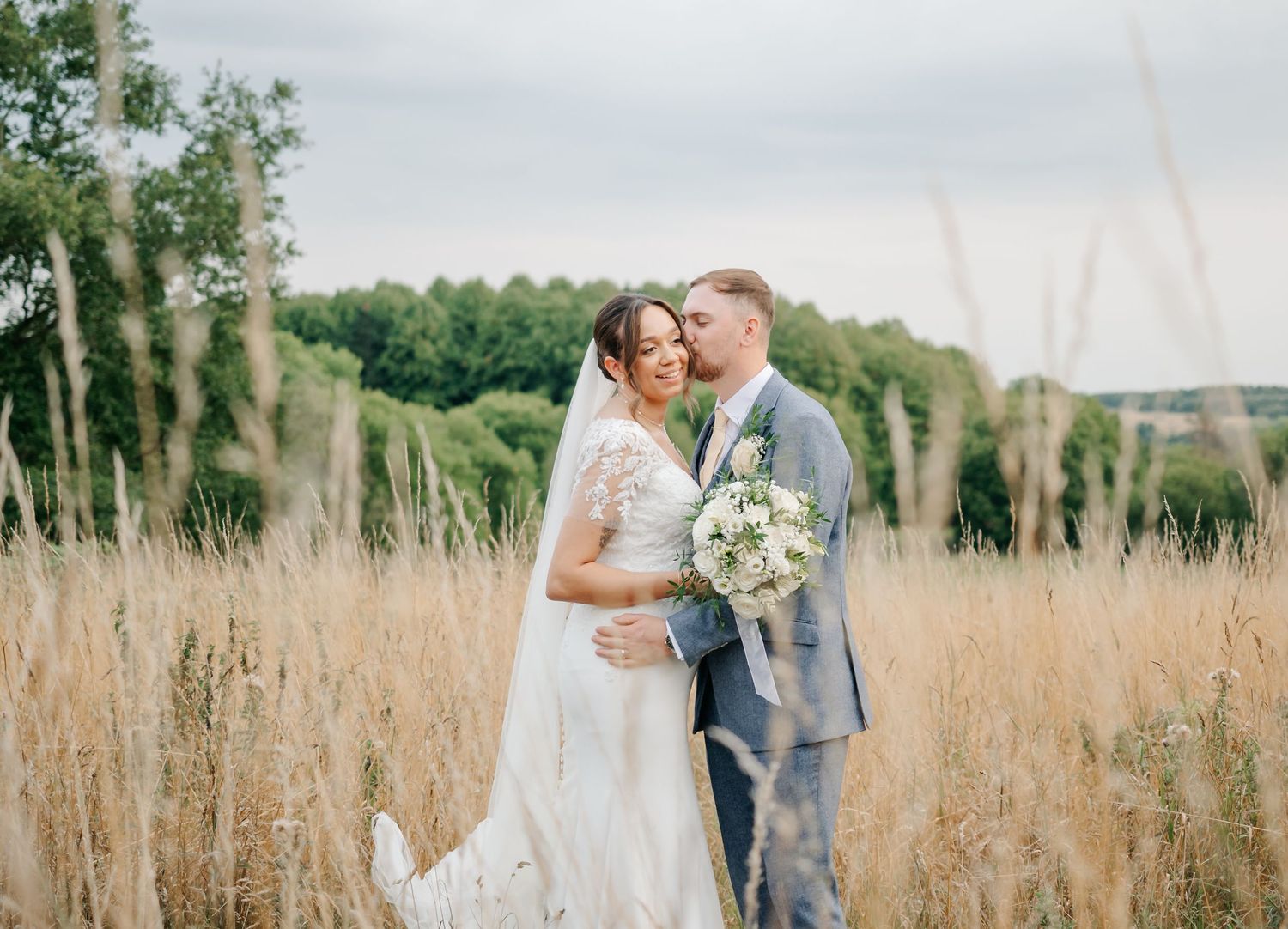 Romantic wedding portraits taken in tall grass field with soft natural lighting.