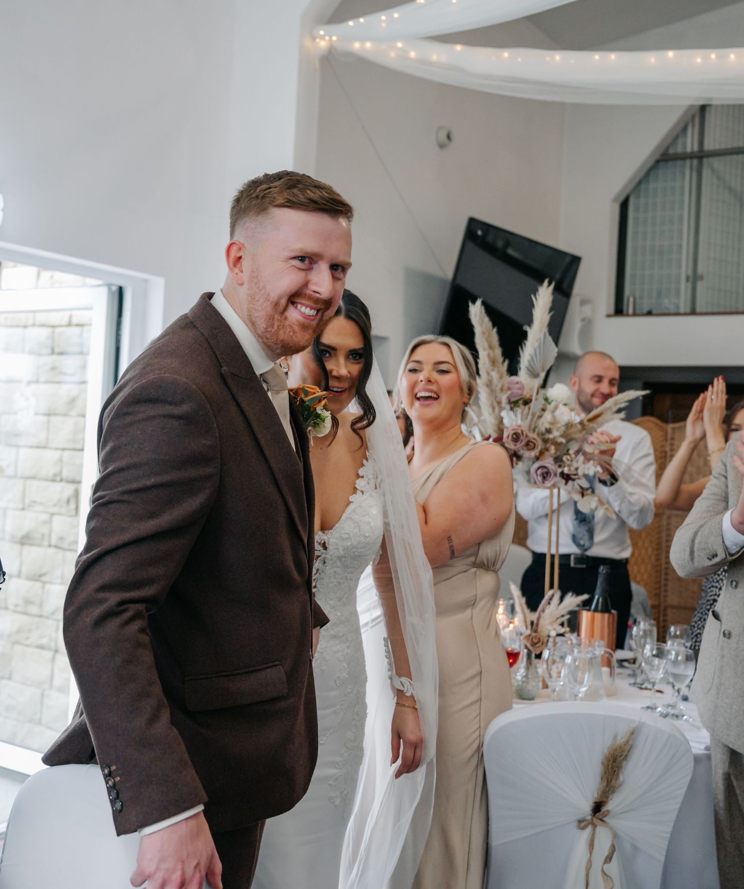 Wedding celebration in a modern white venue with guests sharing joyful moments together.