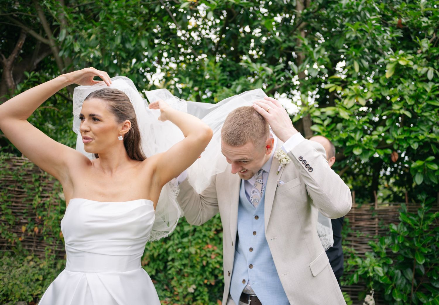 Joyful dancing and celebration at an outdoor wedding with green foliage backdrop.