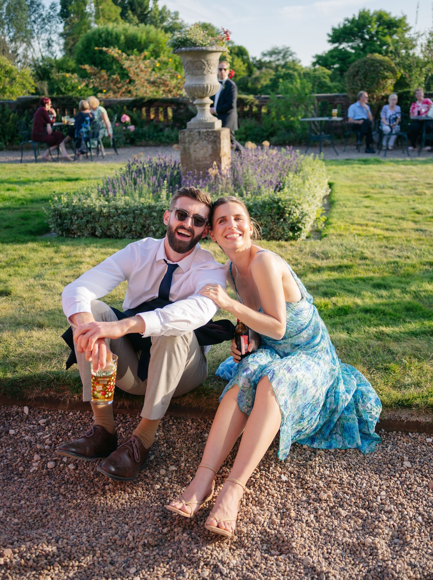 Wedding guests relaxing on gravel path during outdoor summer reception.