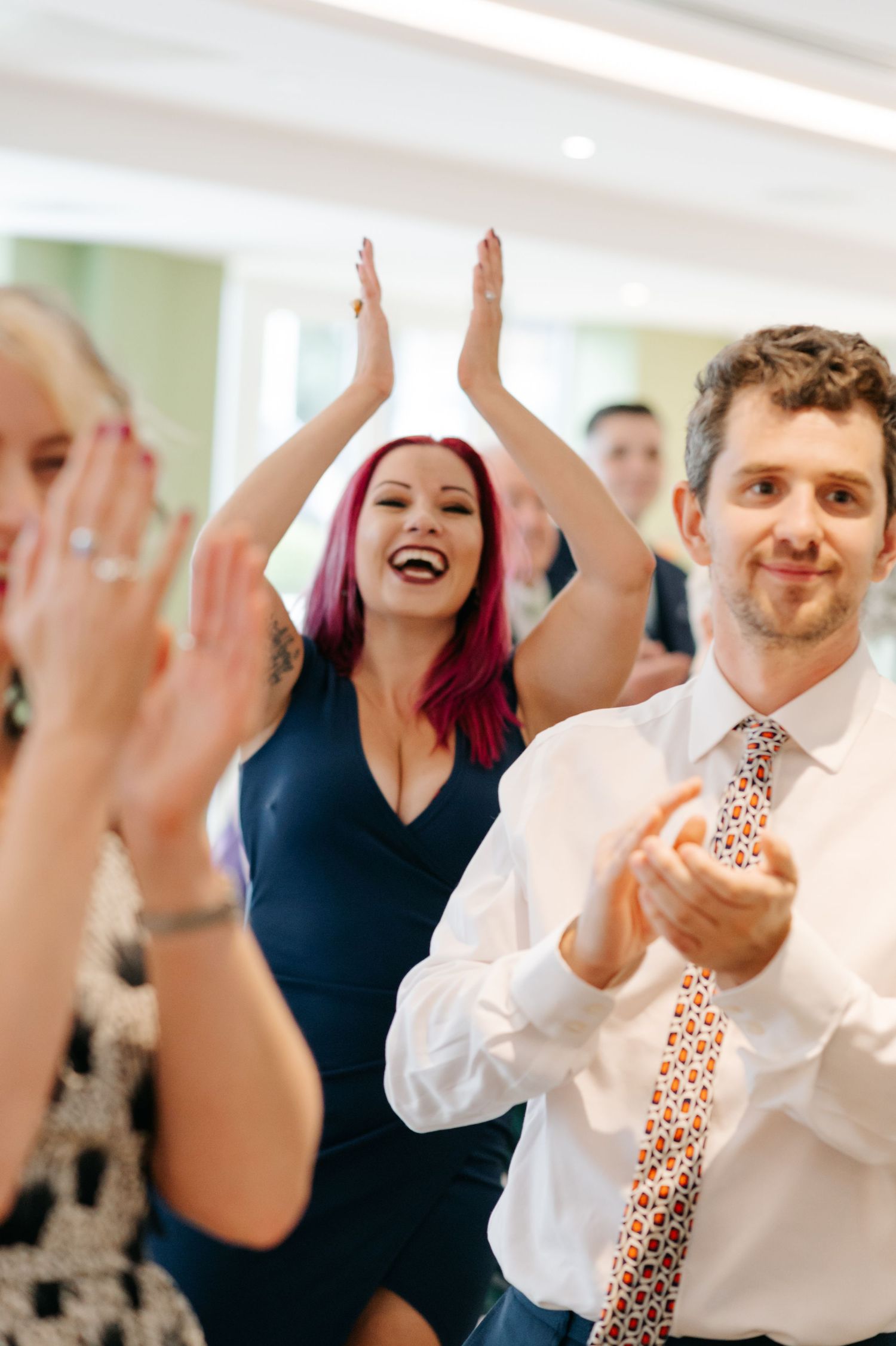 Wedding guests dancing and raising their hands in celebration during a reception party.