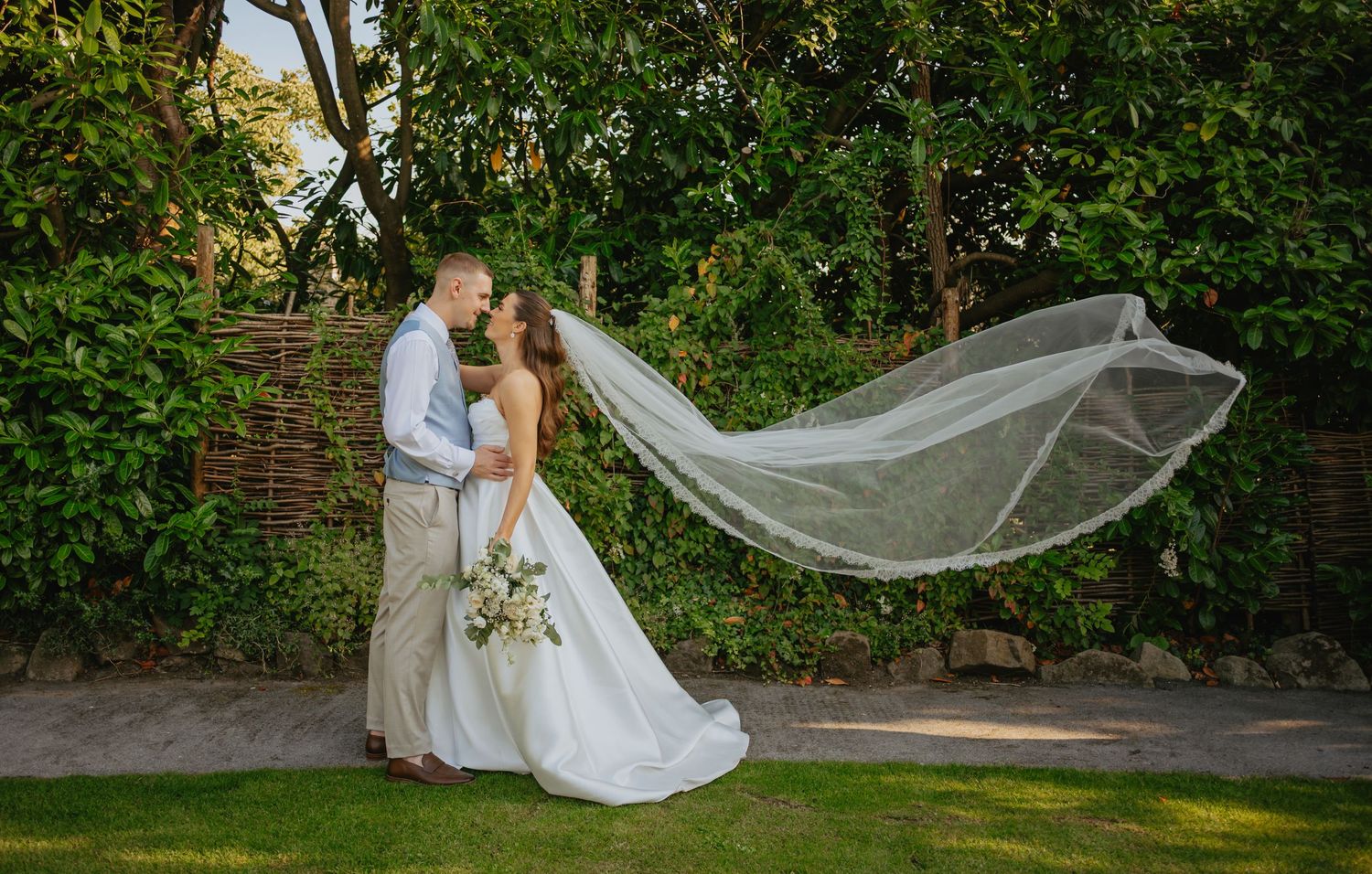 Long flowing wedding veil catching the breeze in a garden setting.
