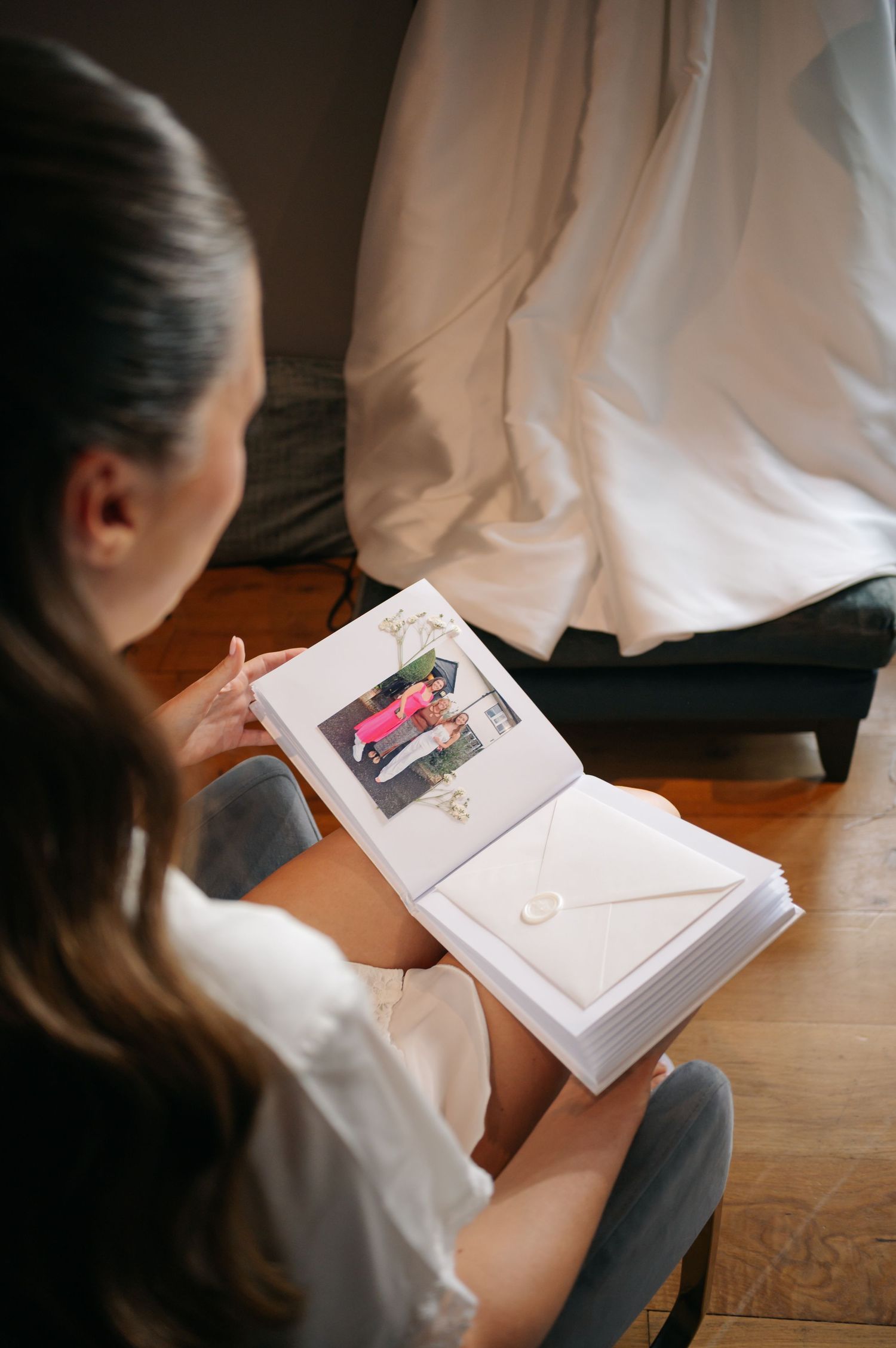 A series of photos showing someone reading a photo album or book while sitting on a wooden floor.