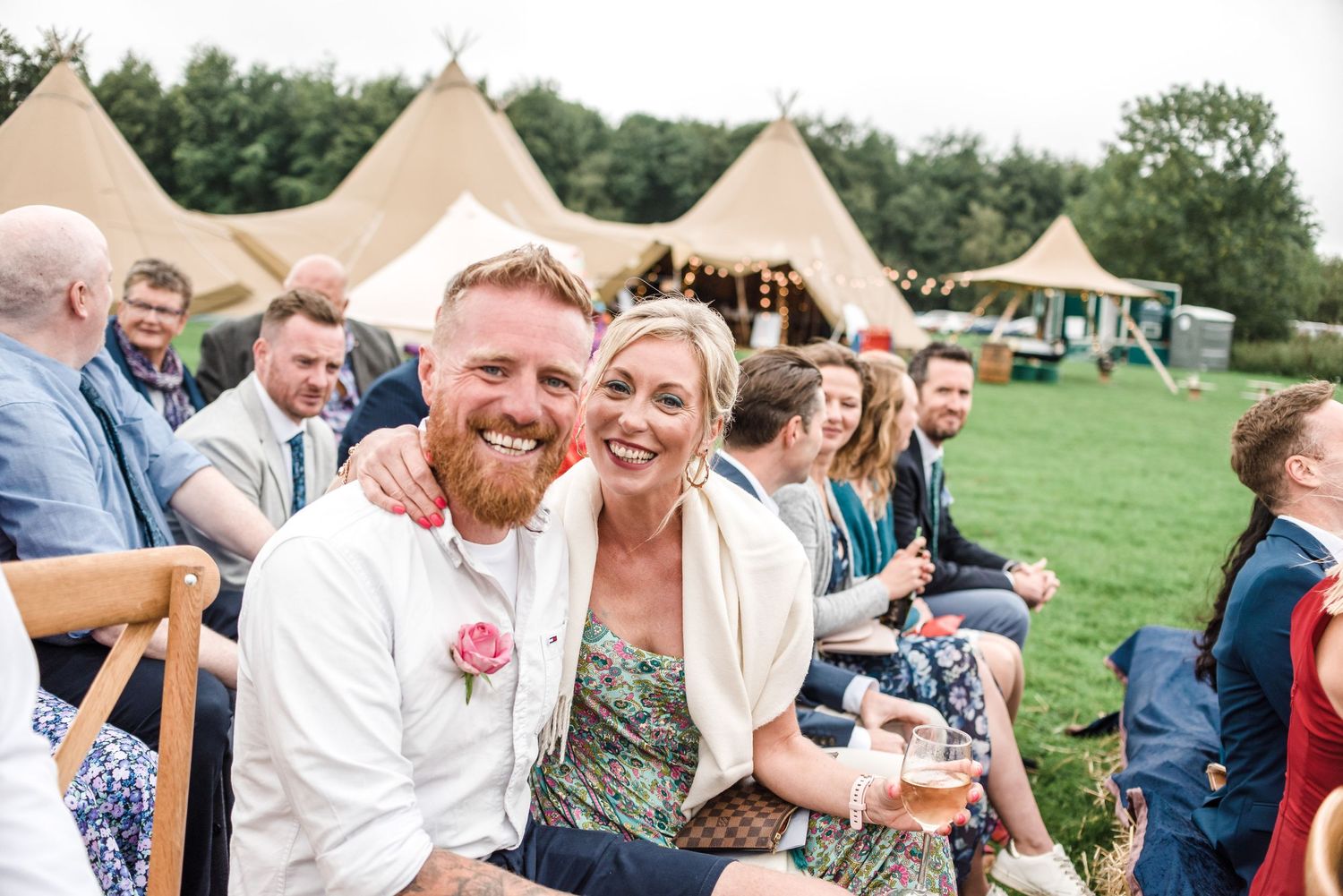 Guests enjoying a celebration outdoors with tipi tents visible in the background.