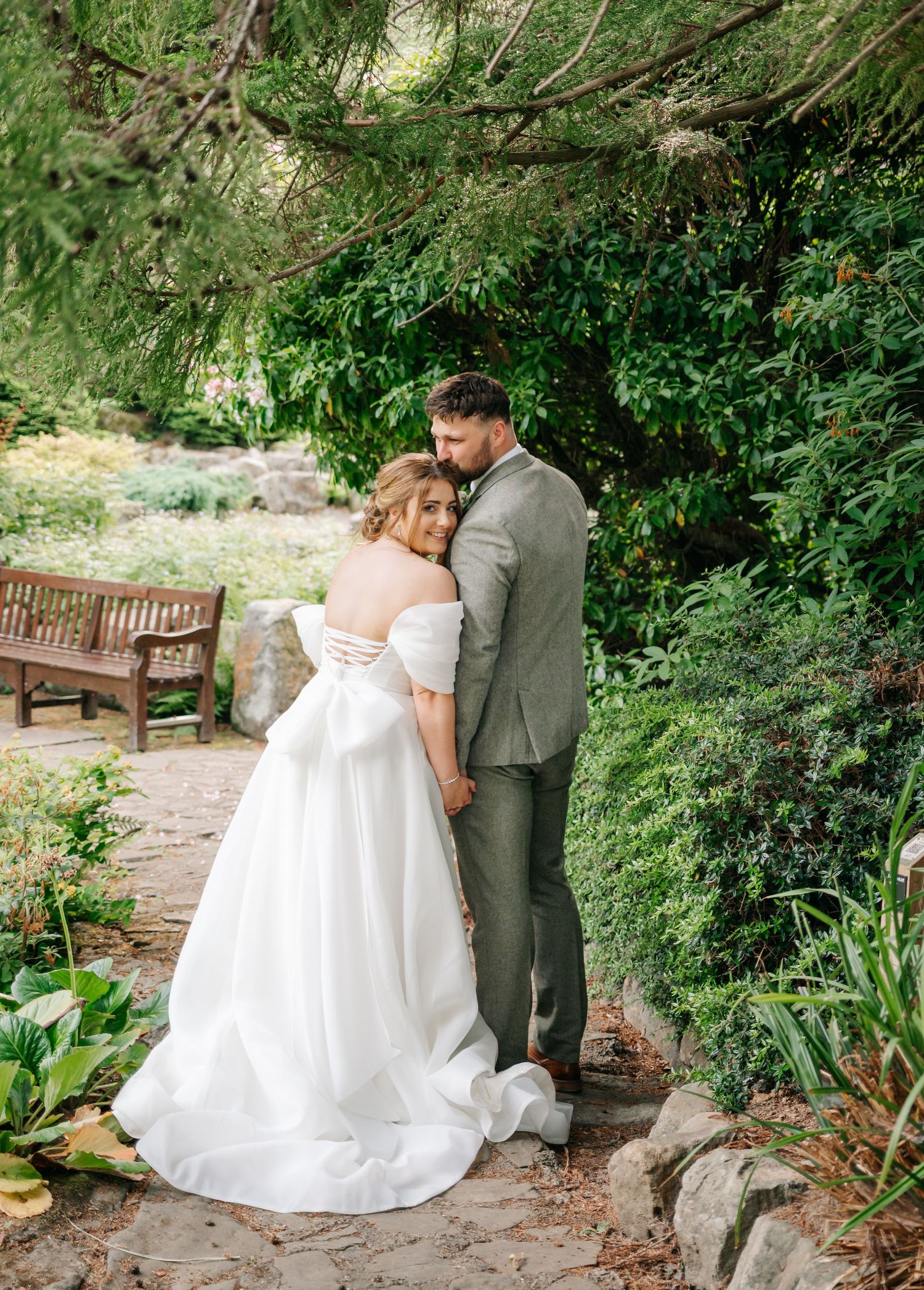 Wedding portraits in a serene garden setting with stone pathways and lush greenery.