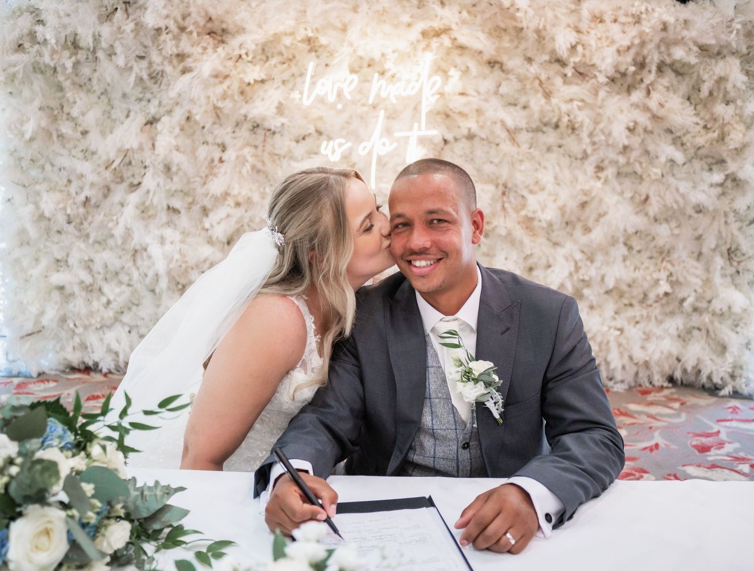 Intimate moment captured during document signing at wedding ceremony.