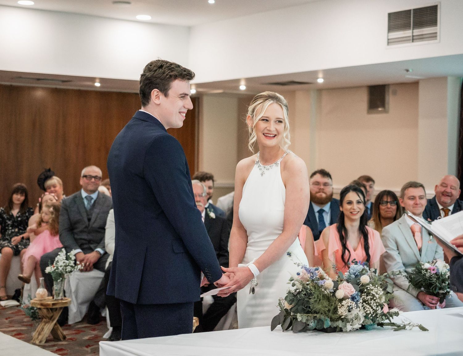 A wedding ceremony in progress in a modern indoor venue with guests watching.
