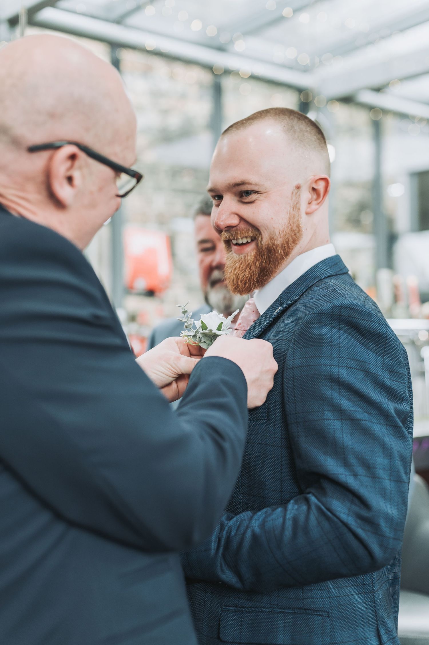 A groom receiving his boutonniere from a guest at the wedding.