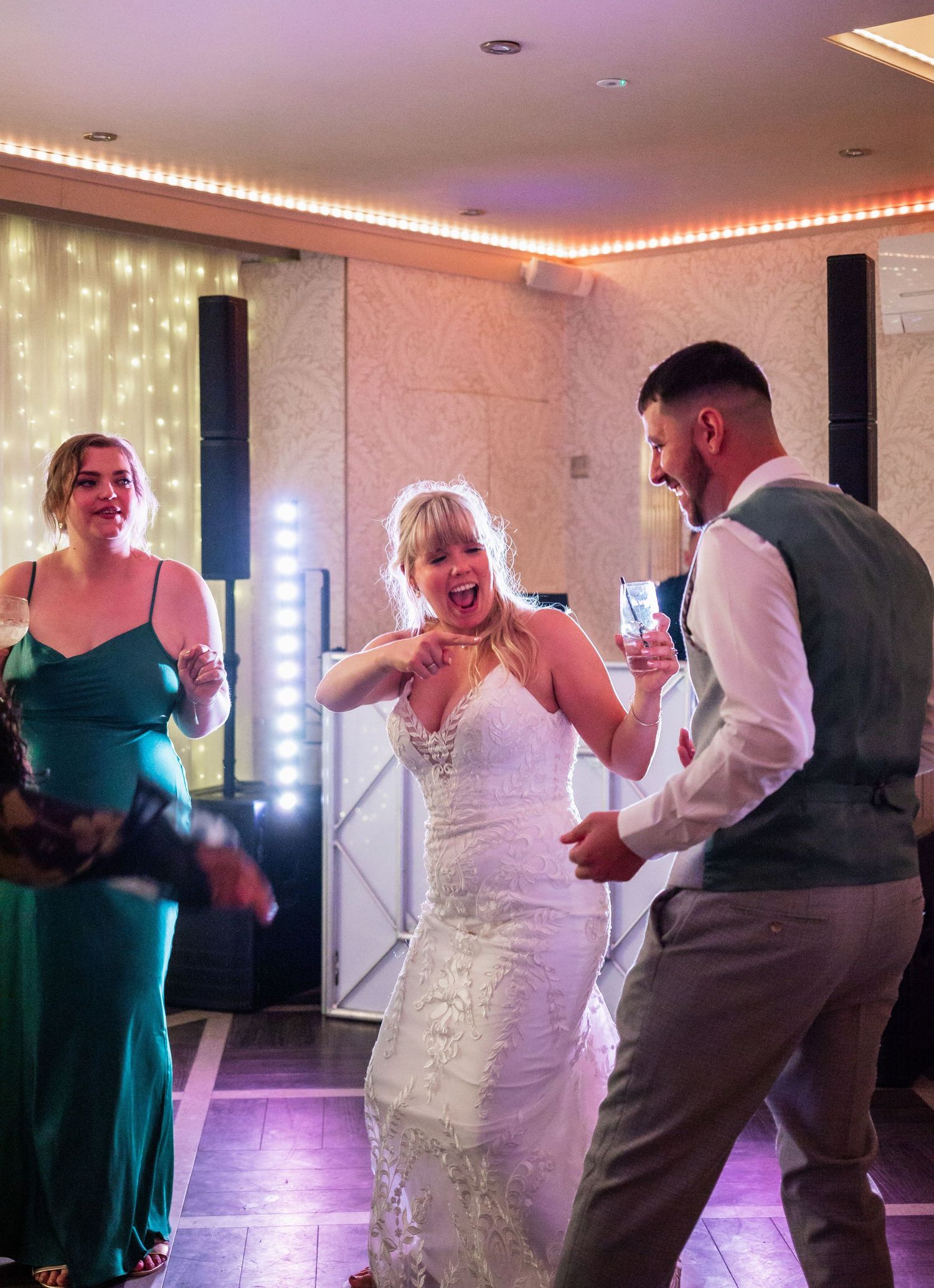 Wedding reception dance floor moment captured with festive lighting and decorative backdrop.
