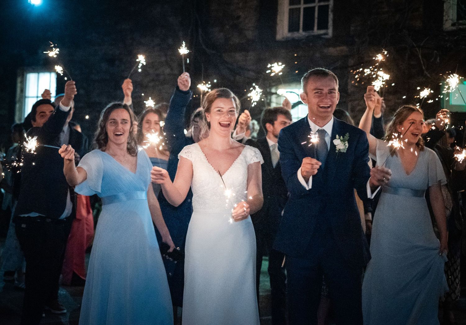 Wedding celebration at night with guests holding sparklers creating a magical atmosphere.