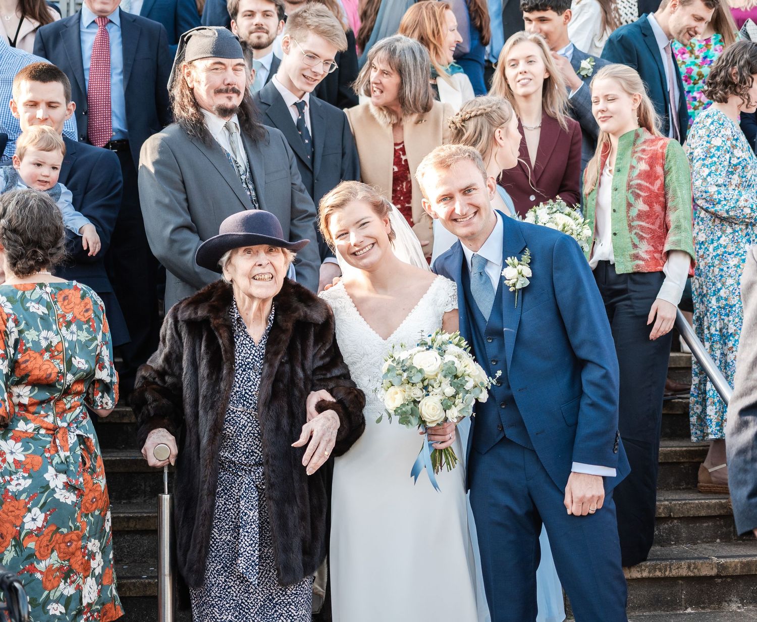 Wedding party celebrates with laughter and smiles on outdoor steps.