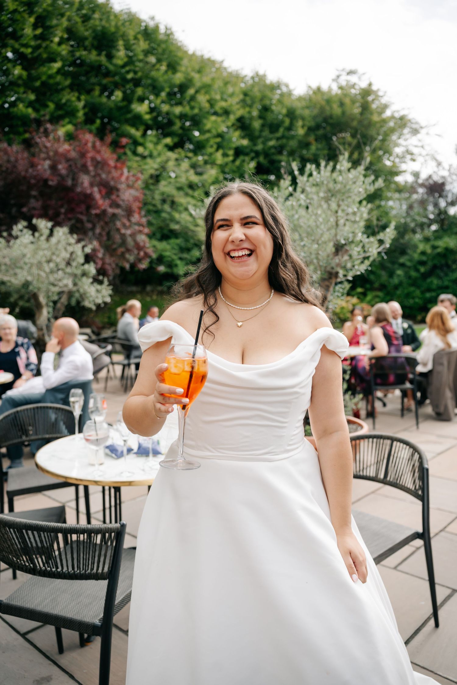 Wedding celebration on an outdoor patio with tables and chairs surrounded by lush greenery.