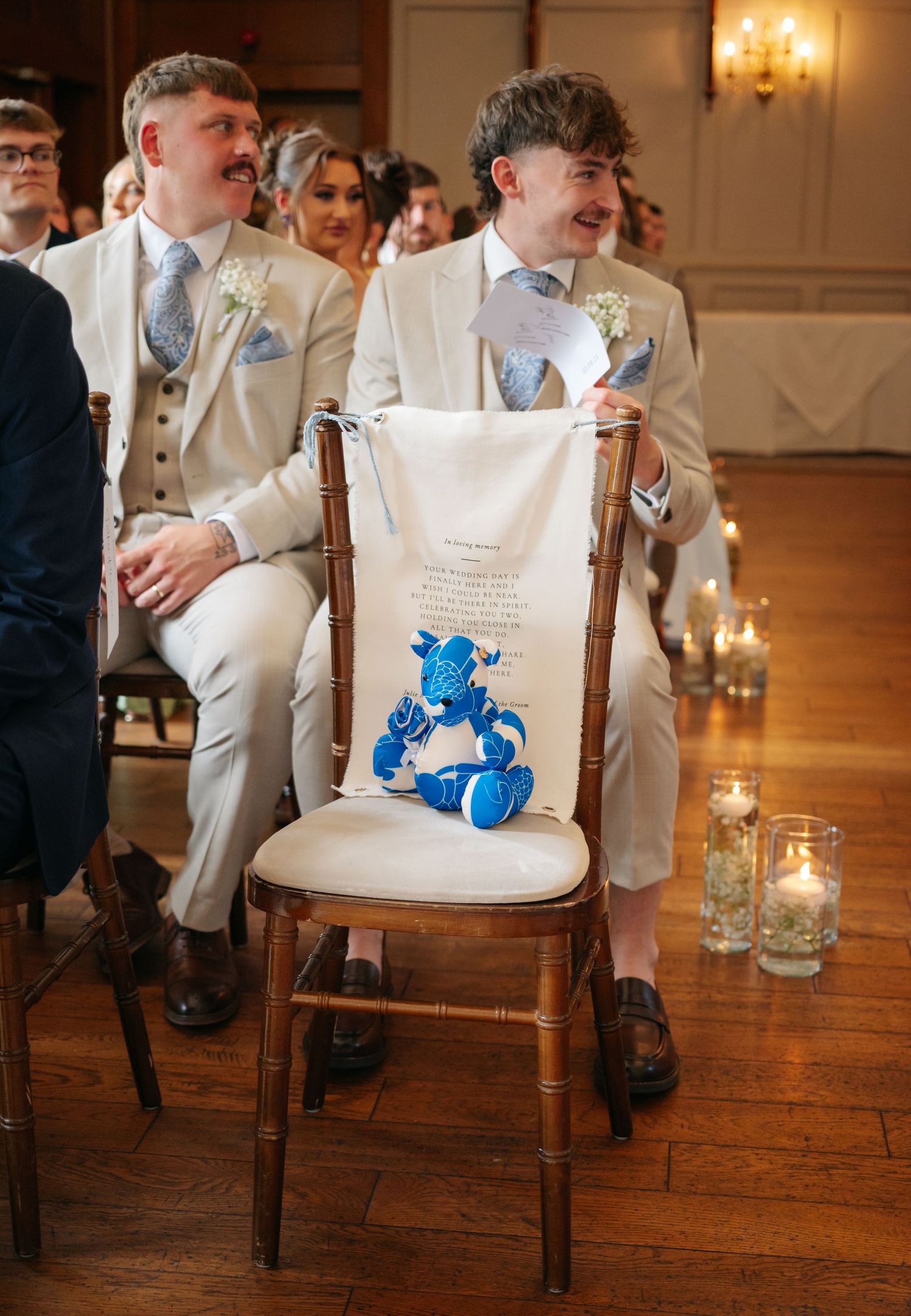 Reception chairs with blue decorative details arranged in rows on a hardwood floor with candlelight.
