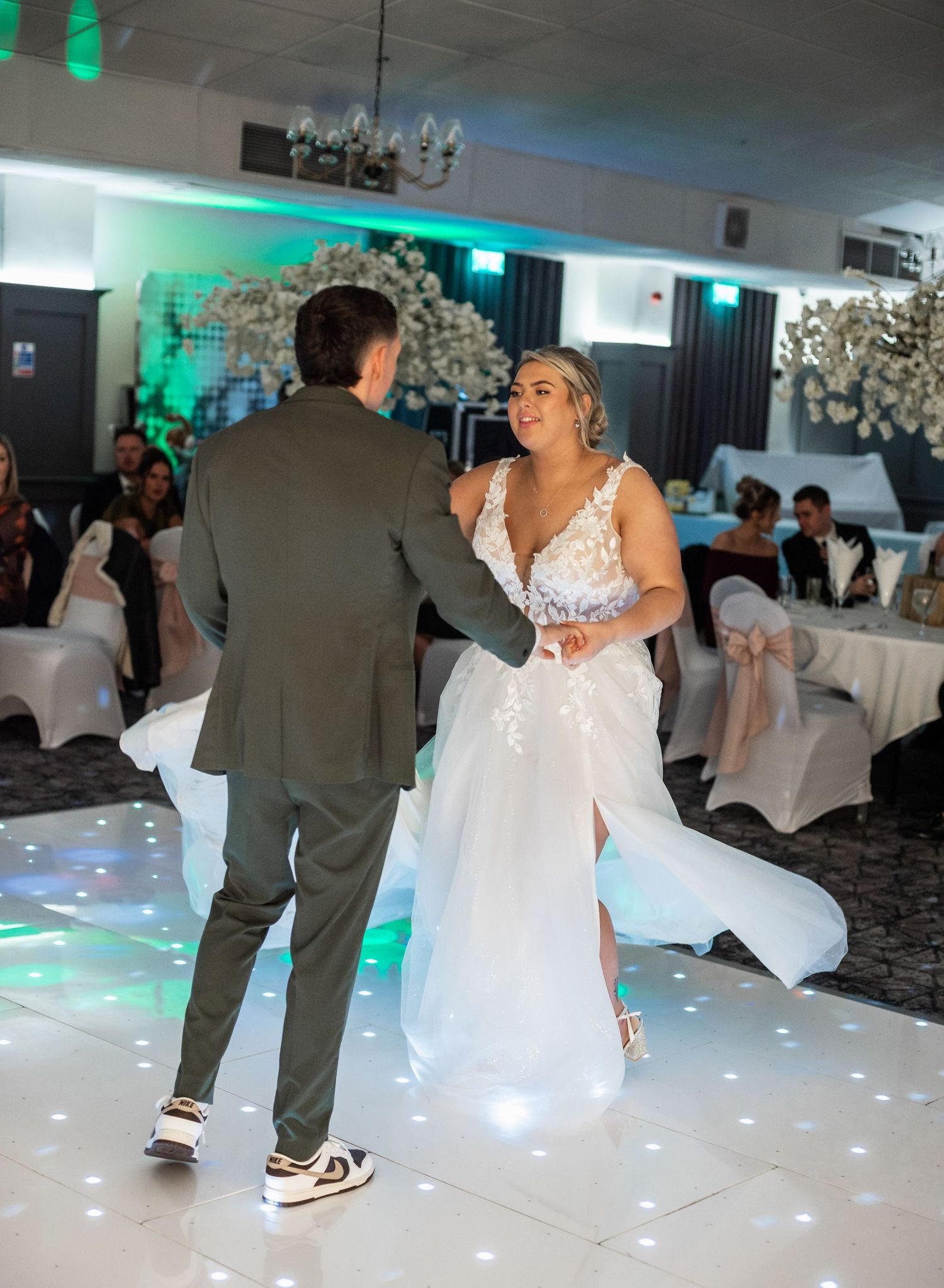 Couple shares first dance on reception floor with decorative lighting.