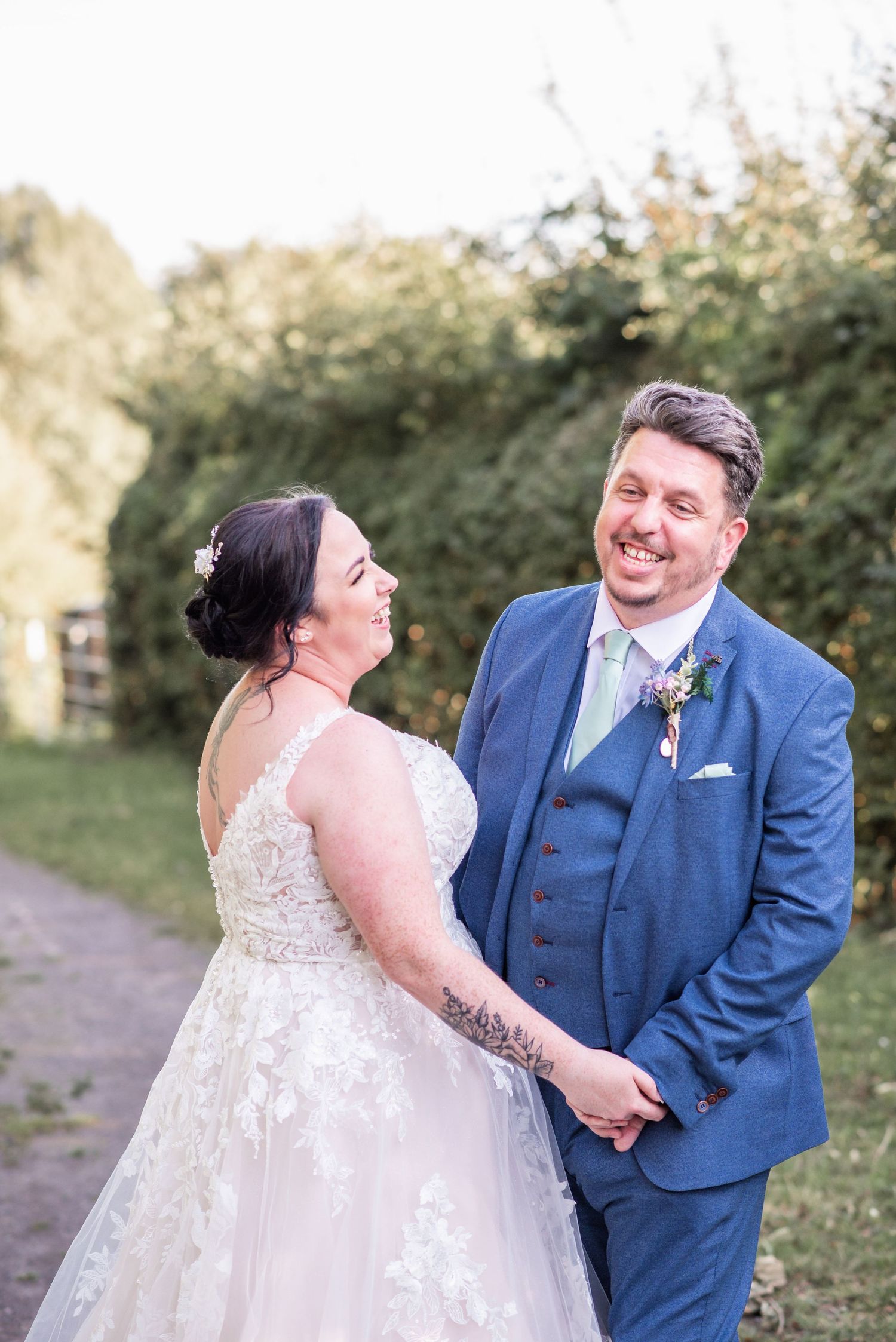 Outdoor wedding portrait on a garden path with natural greenery backdrop.